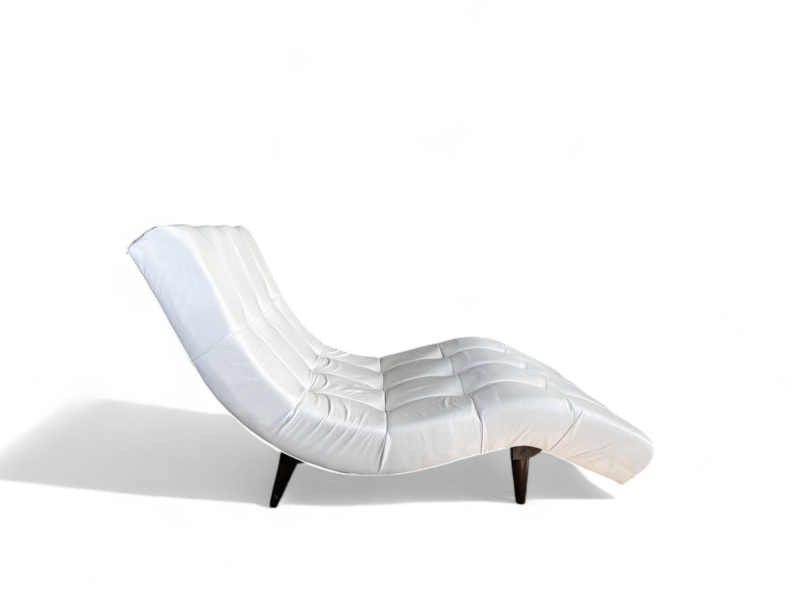 Wavy Chaise Lounge in the Manner of Adrien Pearsall: White pleather upholstery with walnut legs, this tufted wavy chaise lounge is a quick answer for a masterbedroom accent or living room. Place a large sheepskin on top and you are ready to lounge. Meas
