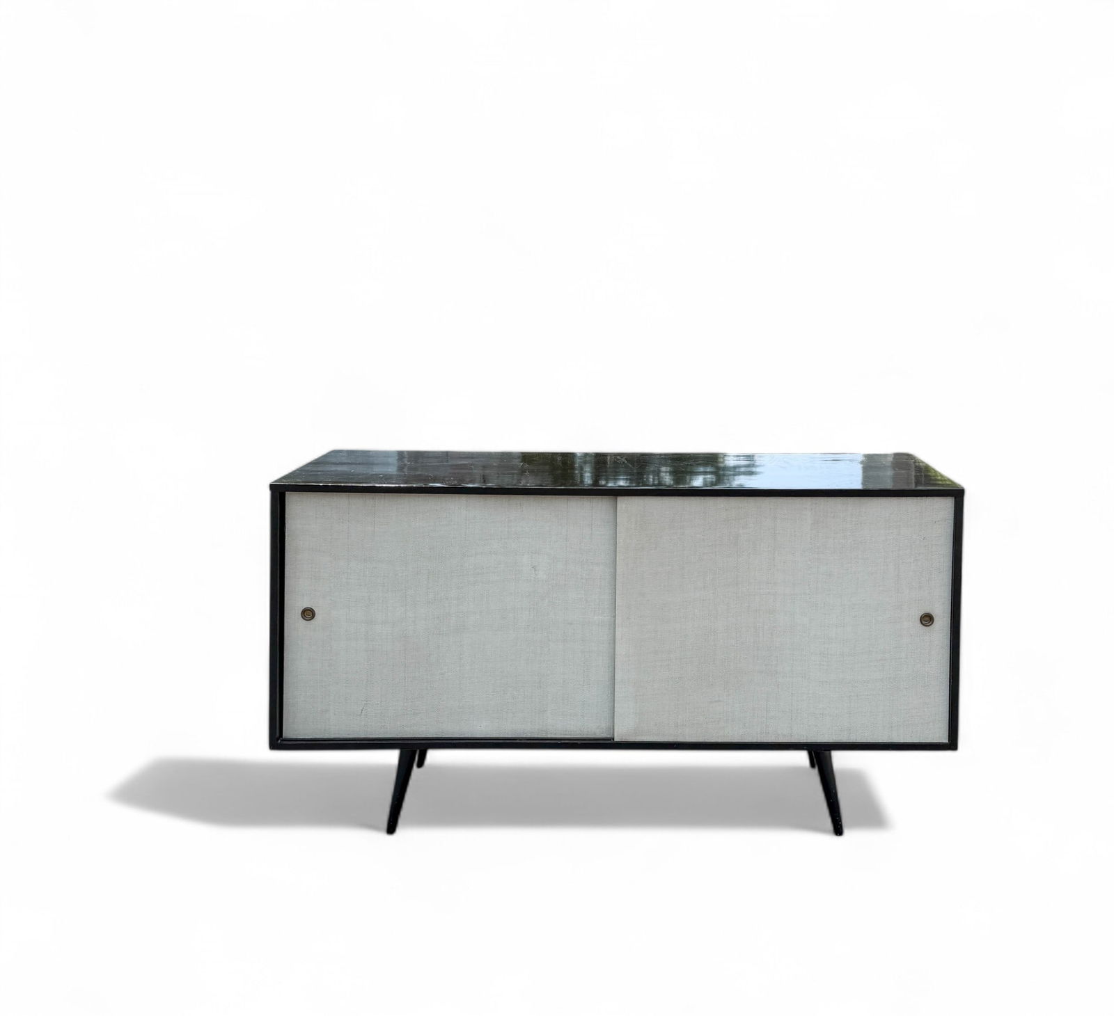 Paul McCobb Planner Group Credenza for Winchendon: Paul McCobb for Planner Group, circa 1950's Mid Century Modern stunner in maple with black lacquer and white cloth covered, sliding front doors with brass cap finger hole and interior adjustable shelf
