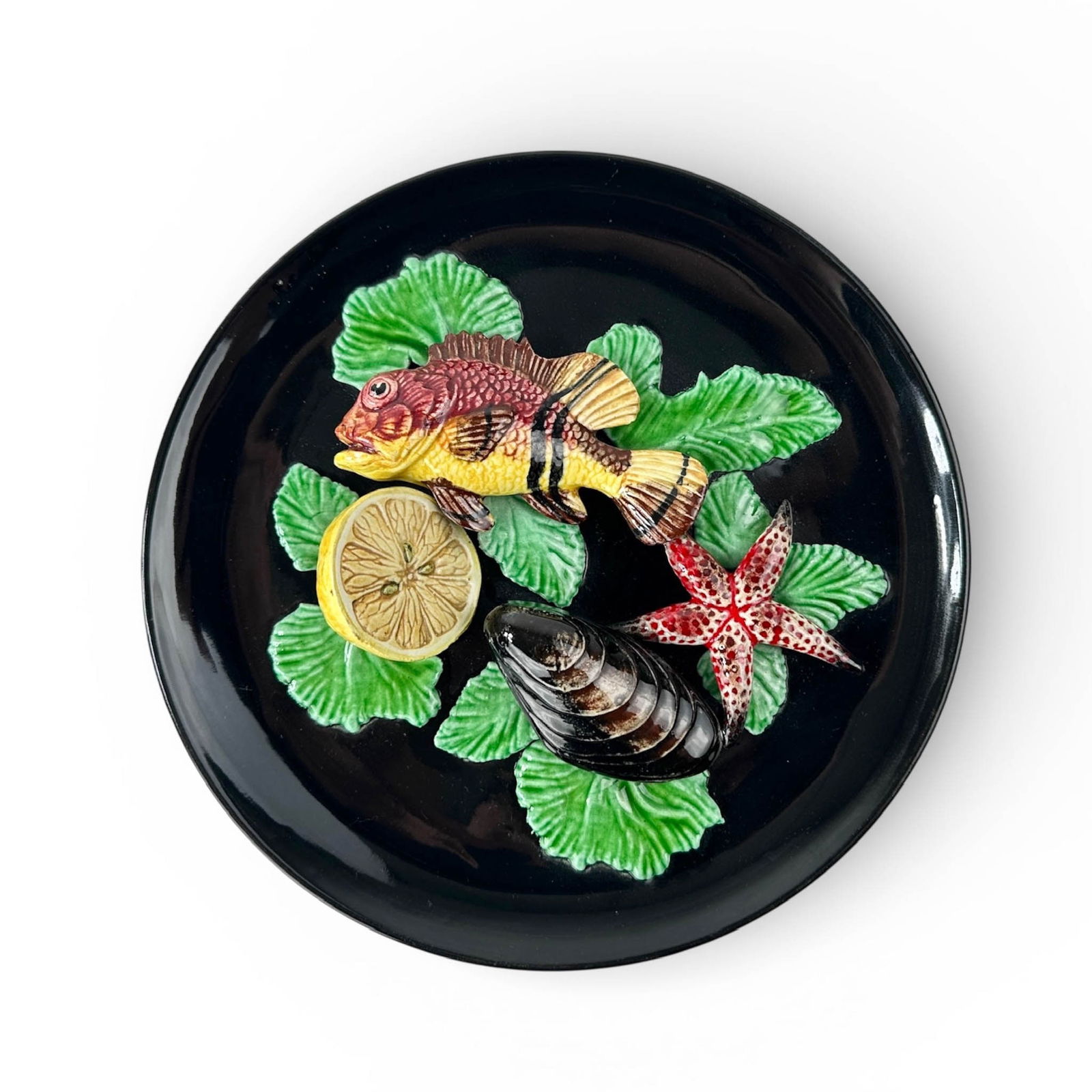 Vallauris French Majolica Sea Life Plate: Stupenduous, French Majolica fish, mussel, starfish and seaweed in relief ceramic plate. Set on black plate background, vibrant green, red and yellow sea life in relief. Import from France, Measures