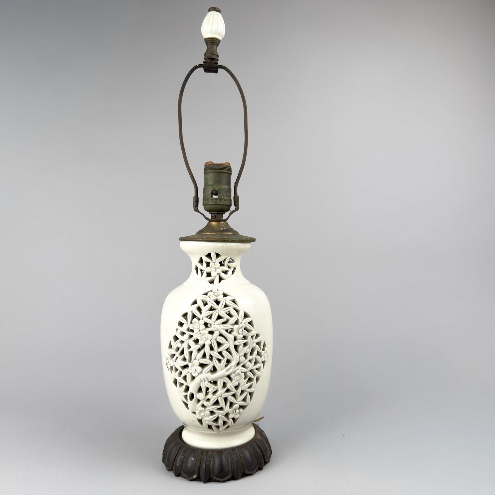 PIERCED BLANC de CHINE TABLE LAMP: Antique blanc de chine, porcelain urn shaped table lamp with pierced or reticulated cherry blossom pattern sits on a carved rosewood base. 20 5/8" h (to top of finial), 5 inches in diameter