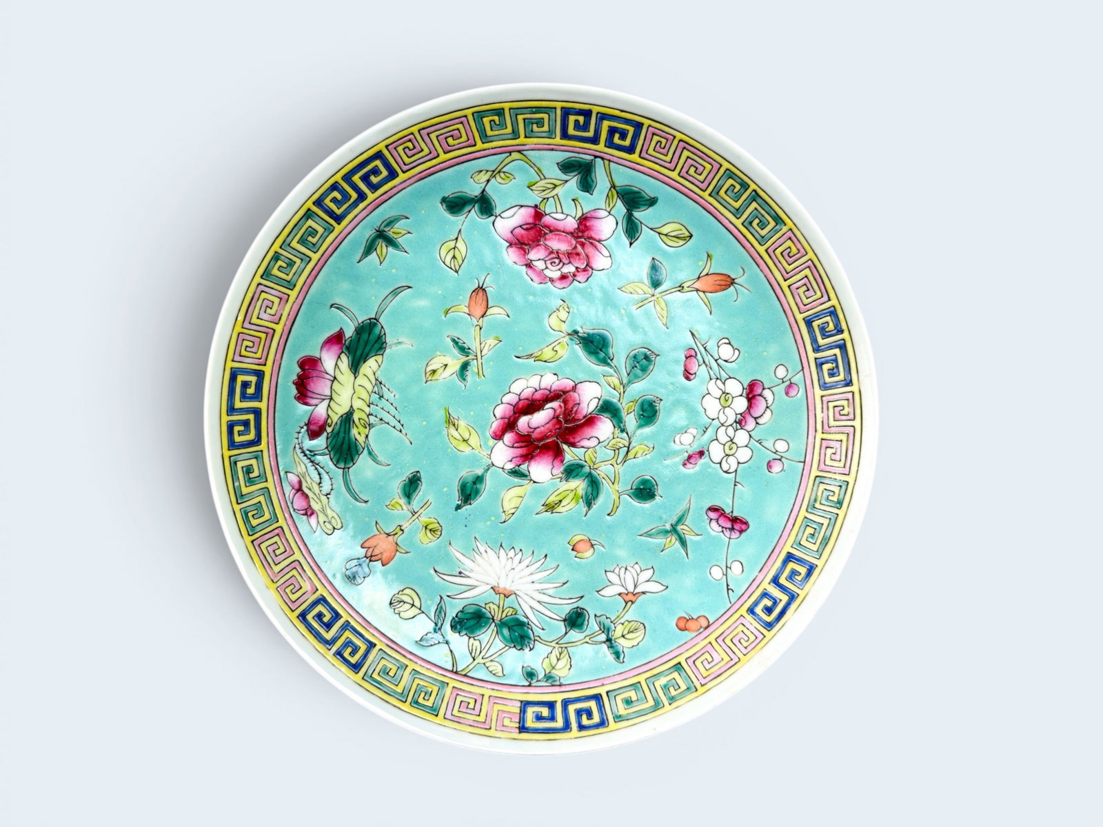 CHINESE MUN SHOU FAMILLE ROSE TURQUOISE GROUND PLATE: Circa early 20th century, Chinese Mun Shou Famille Rose chinoiserie porcelain plate with turquoise ground, floral motif and greek key border. 9" Diameter, 1 1/2" H