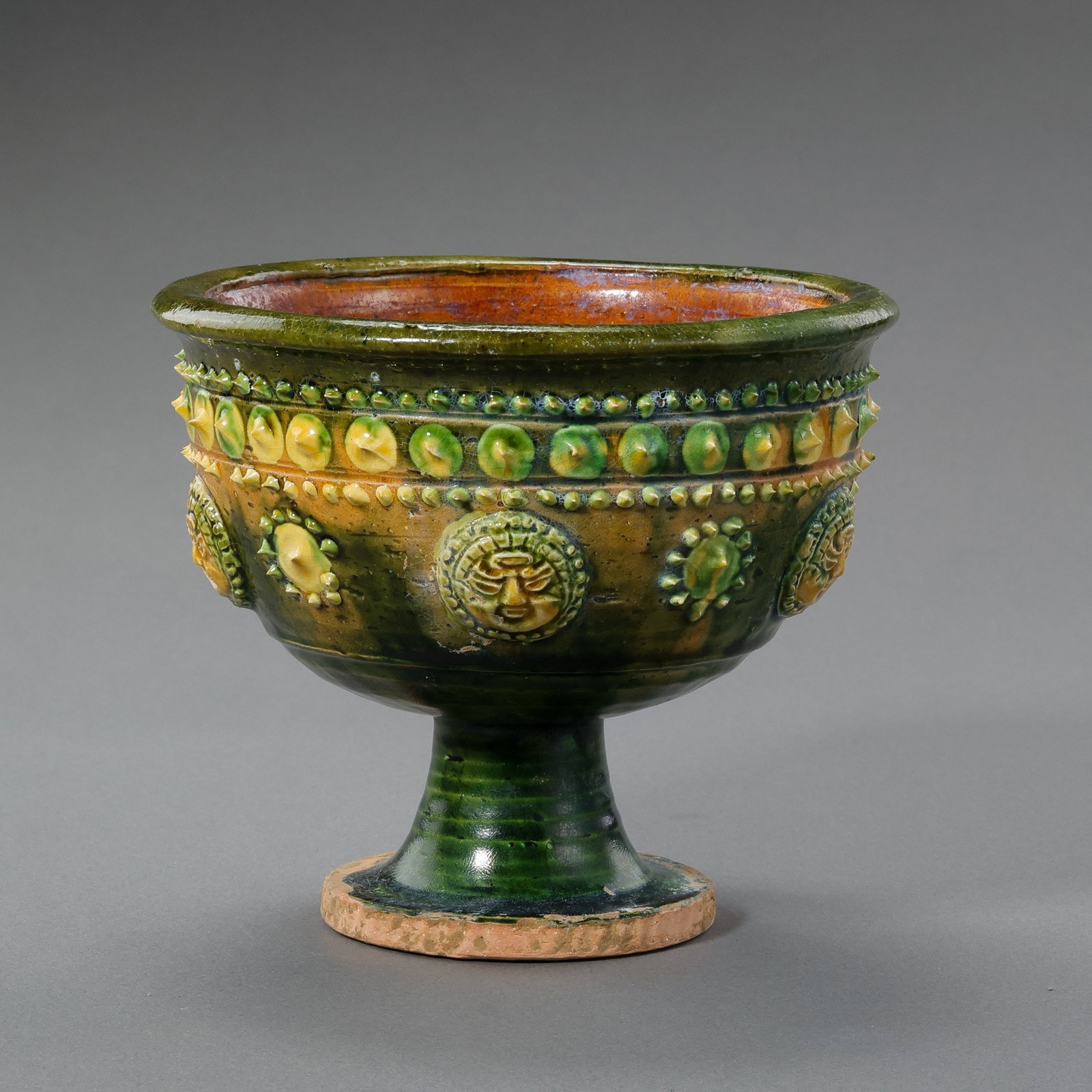 A Chinese Sui Dynasty yellow-green glazed stem cup with applied drum nail patterns.: H. 10 cm. Diam. 12.4 cm.
