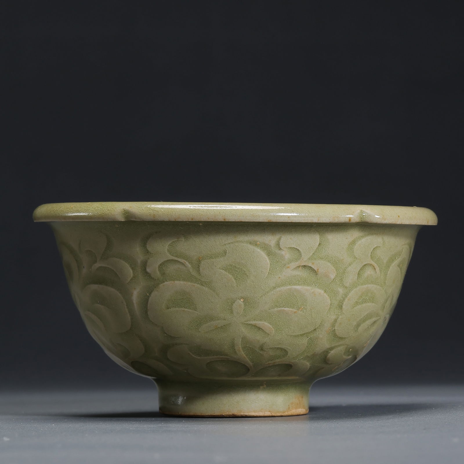 A flower-shaped cup with carved floral patterns from the Yaozhou kiln during the late Tang and Five: H. 5.5 cm. Diam. 9.7 cm.