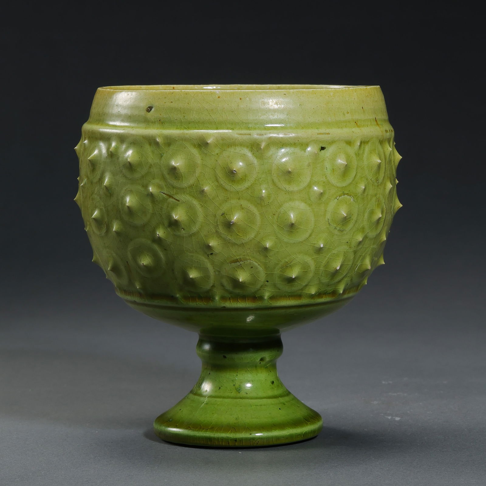 Chinese Sui Dynasty Green-glazed Drum-nail Pattern Stem Cup: H. 11.8 cm. Diam. 10.8 cm.