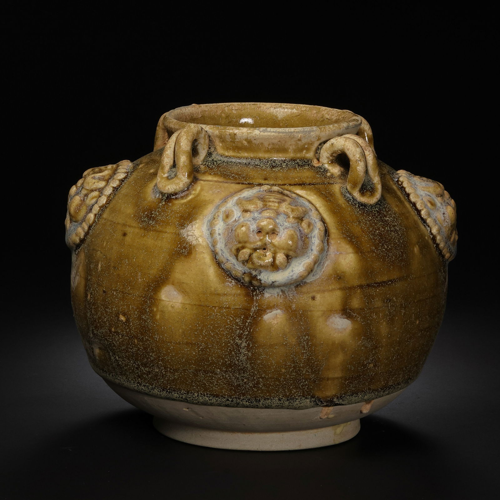 A celadon jar with four handles and appliquéd animal heads from the Xiangzhou kiln of the Sui: H. 13.5 cm. W. 16 cm.