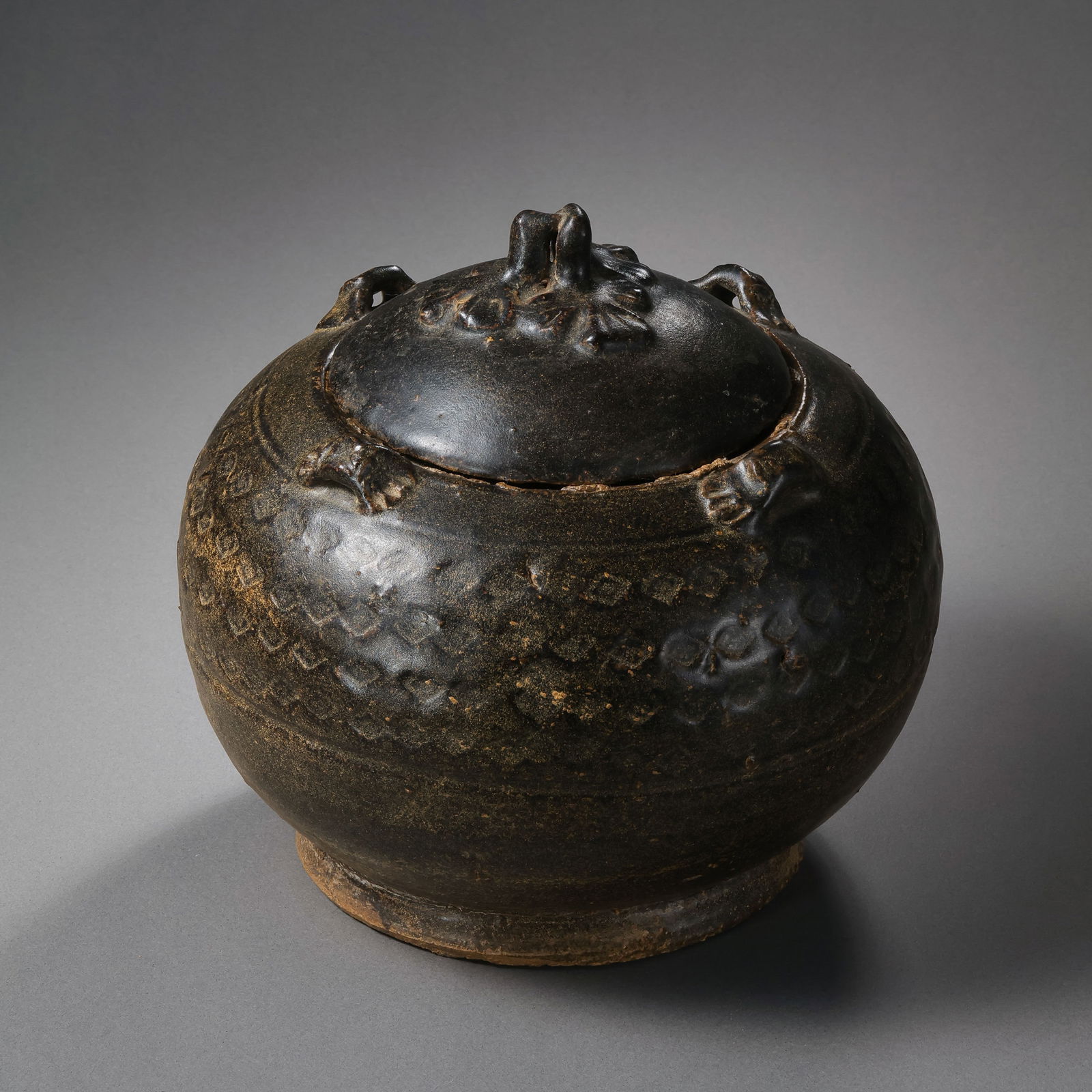 Black-glazed four-handled covered jar from the Northern and Southern Dynasties period of China: H. 16 cm.