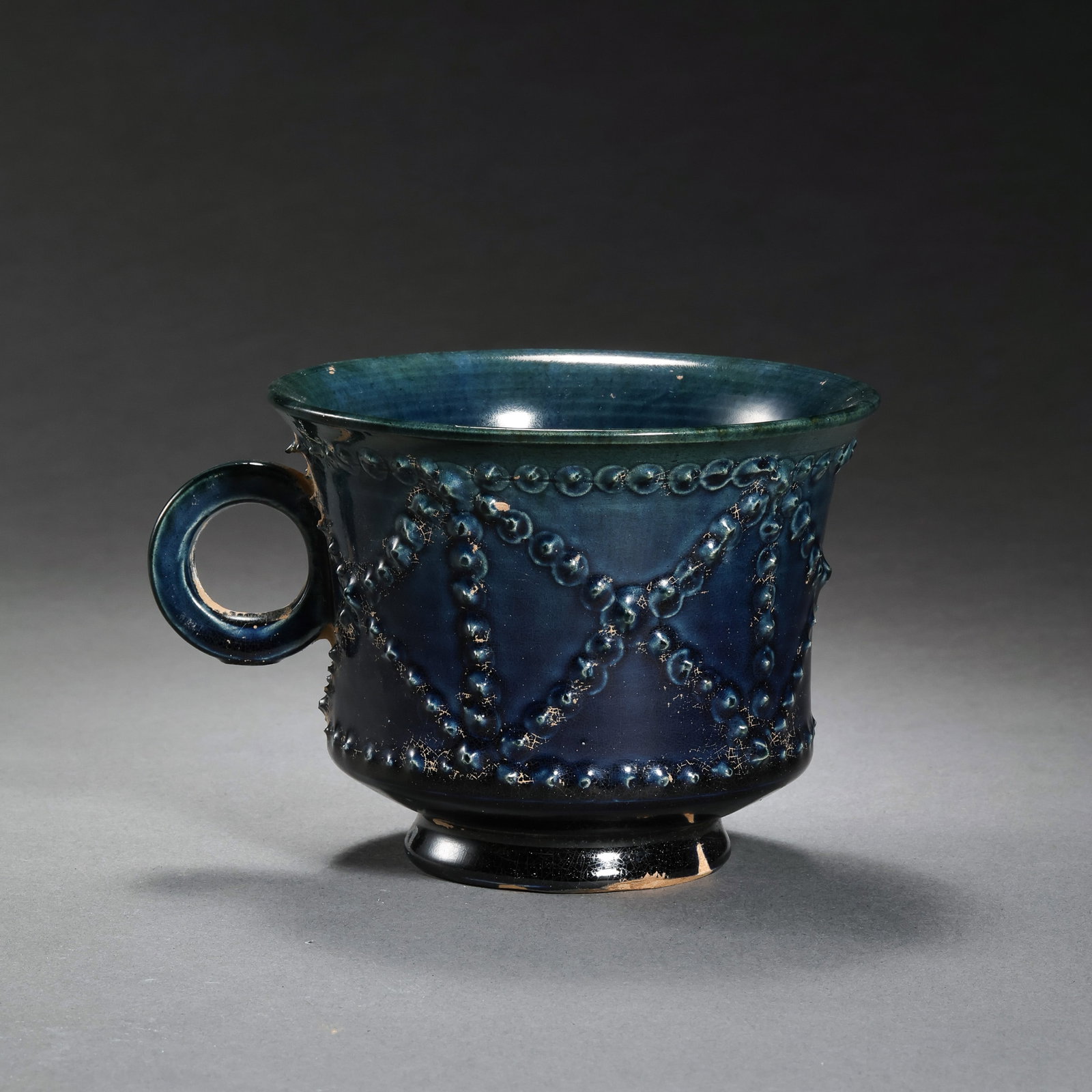 Chinese Sui Dynasty Blue Glazed Drum-Nail Pattern Handled Cup: H. 6.8 cm. W. 10.5 cm.