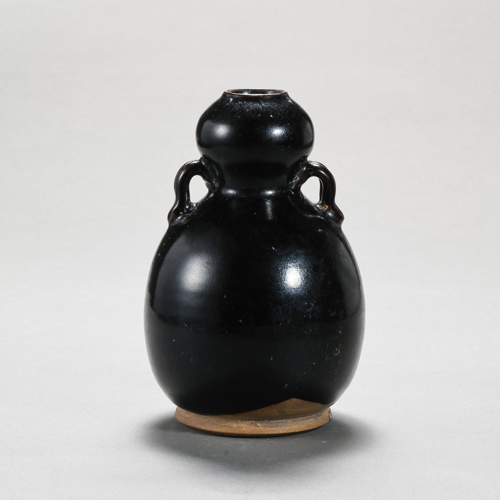 Tang Dynasty Gongxian Kiln Black Glazed Gourd-Shaped Double-Handled Bottle: H. 14.5 cm. W. 9.8 cm.