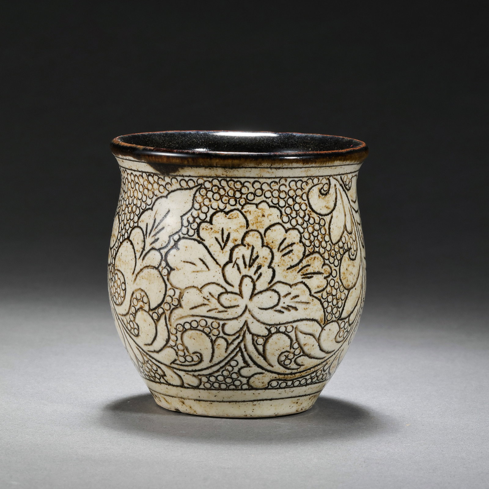 A white-glazed cup with carved floral patterns from the Cizhou kiln of the Northern Song Dynasty,: H. 7.5 cm. Diam. 7 cm.