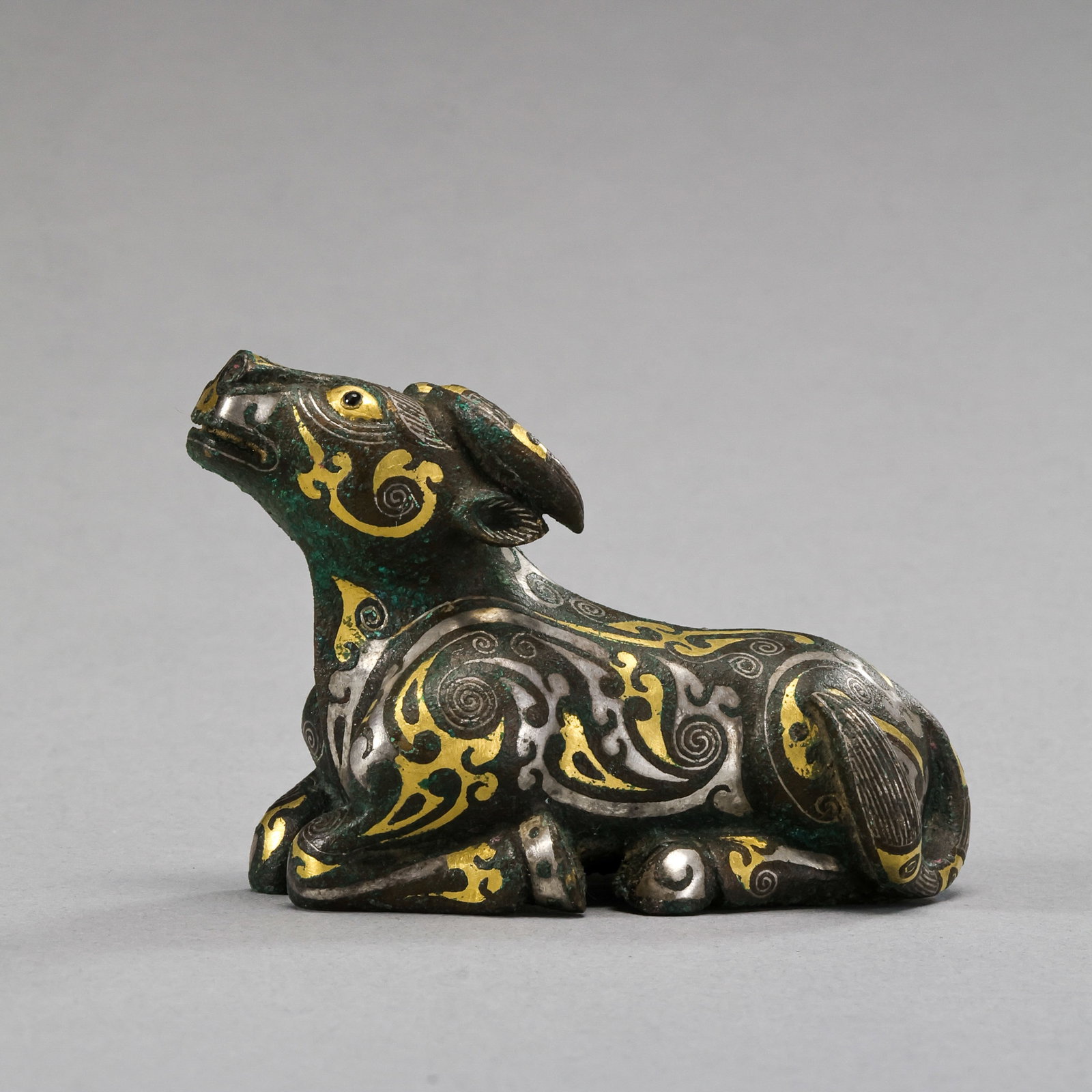 A reclining ox inlaid with gold and silver from the Warring States period in China: H. 4.5 cm. W. 7 cm. Weight. 239 gram.