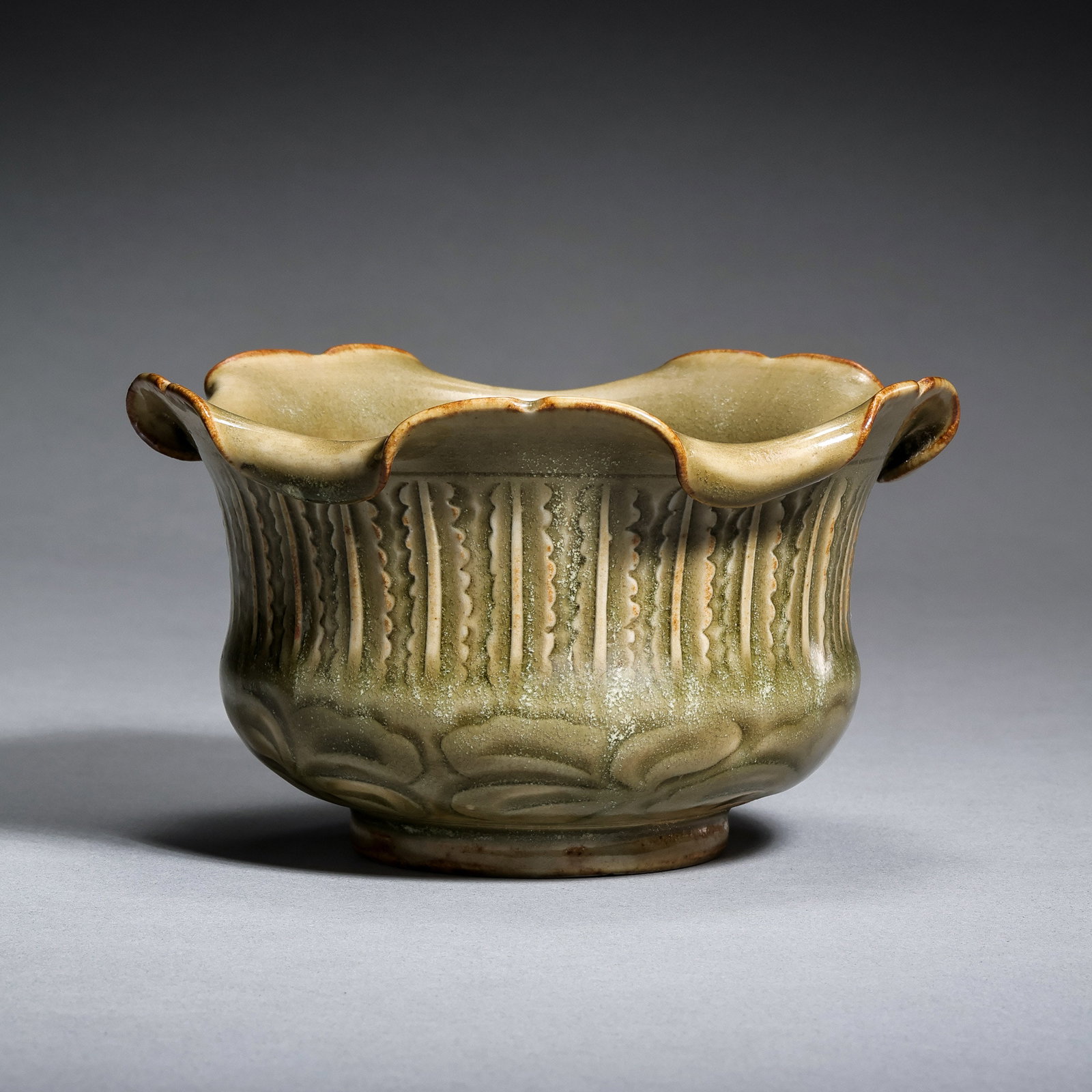 A celadon-glazed spittoon with a flower-shaped rim from the Yaozhou kiln during the late Tang and: H. 6.8 cm. Diam. 12.5 cm.