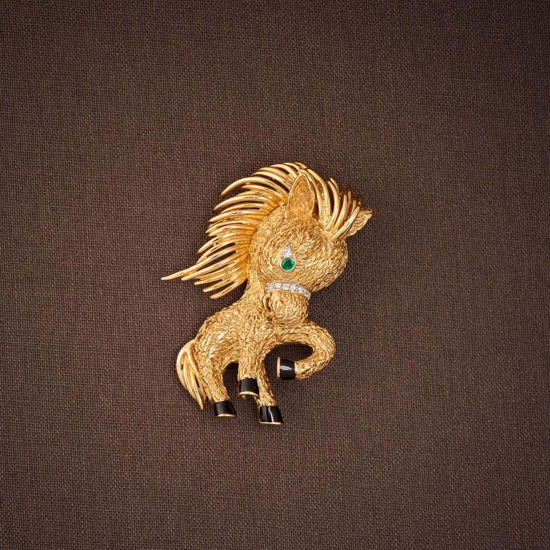 VAN CLEEF & ARPELS BROOCH: In 18K yellow gold, featuring a pony with a small emerald in the eye and a collar of very small diamonds. The hooves are enhanced with black enamel. Work c. 1960. Marked: 750, VCA, n° 105034, dat