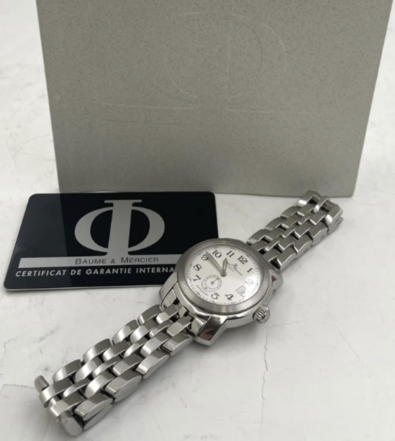 Baume & Mercier Stainless Steel Men's Watch MV045221: Baume & Mercier Stainless Steel Men's Watch MV045221. Baume & Mercier stainless steel men's watch, made in Geneva, with a quartz movement, with a white face and Roman numerals. It measures 39 mm in wi