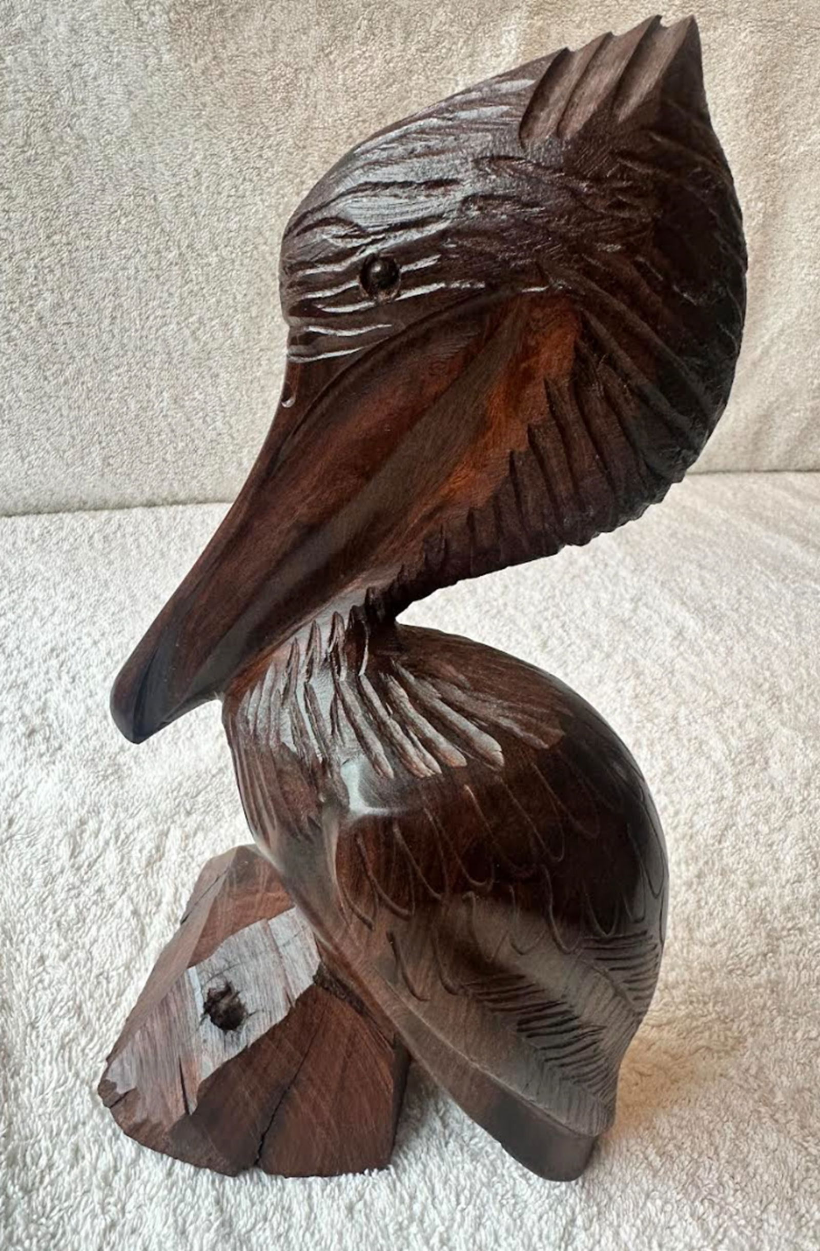Hand Carved Ironwood Pelican Figurine Statuette Circa 1987: This striking vintage ironwood pelican captures the quiet grace and commanding presence of a great waterfowl at rest. The sculpture showcases the natural beauty of dense ironwood, with its rich dark t
