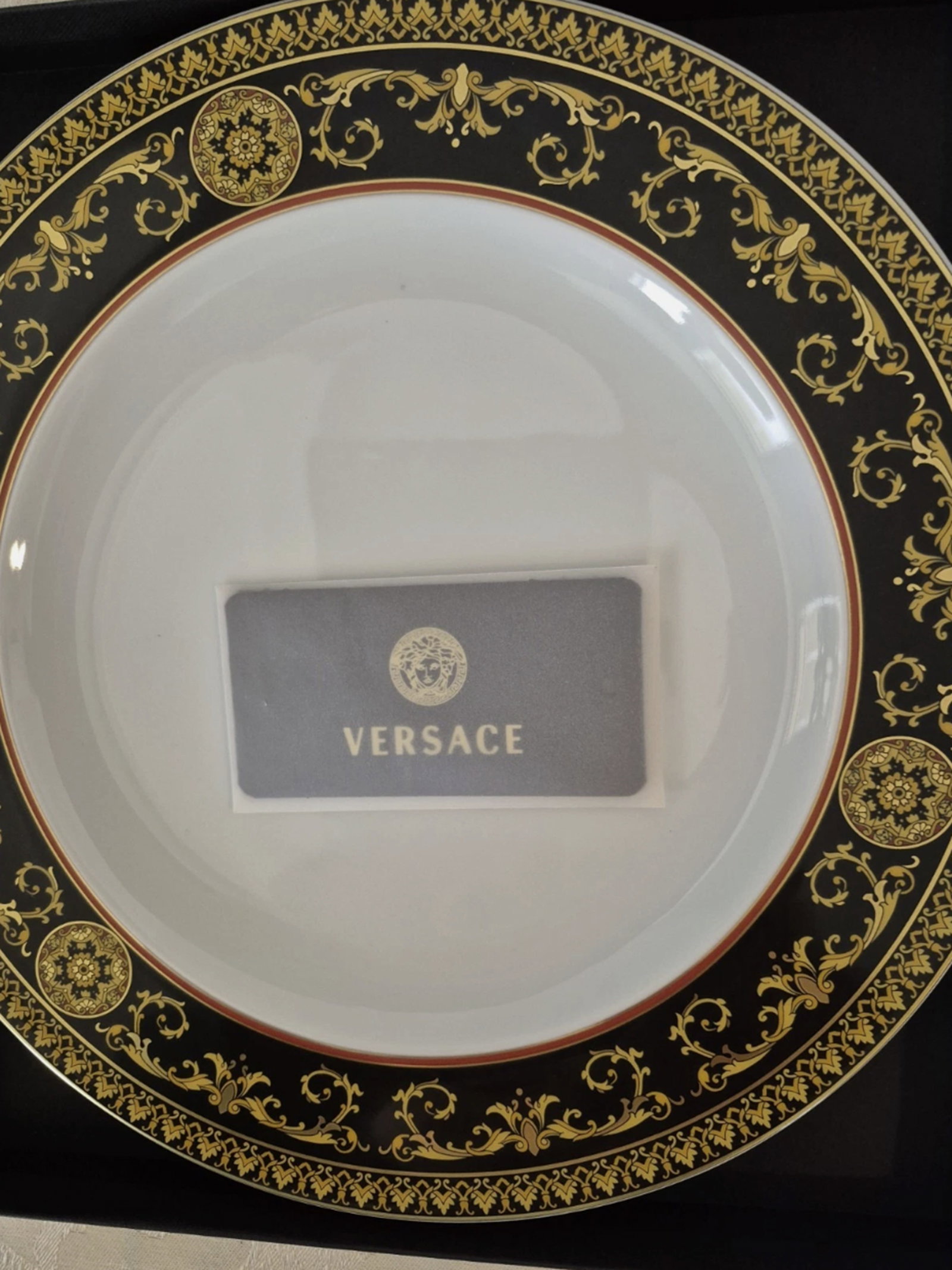 Versace Medusa Dinnerware With Original Box: The Versace Medusa 27' Plate is a decorative collector's item made of porcelain, featuring a round shape and a decorative style. Produced with an art pottery technique in the 2020s, this plate comes