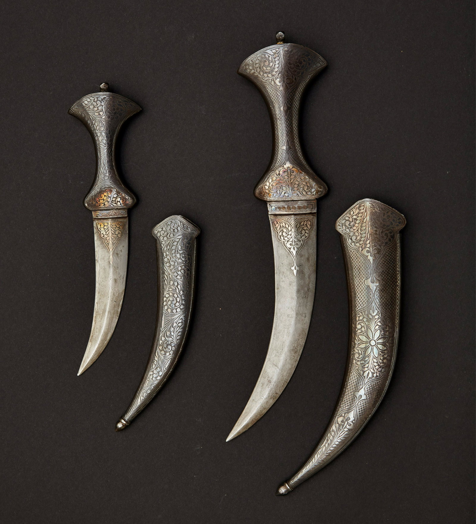 Zwei Arabische Djambia 19. Jahrhundert.: Curved damascus dagger blades without a pronounced center ridge. Both sides of the blade have silver floral arabesques in relief, which merge into patterns at the raised base of the blade. The hilt an