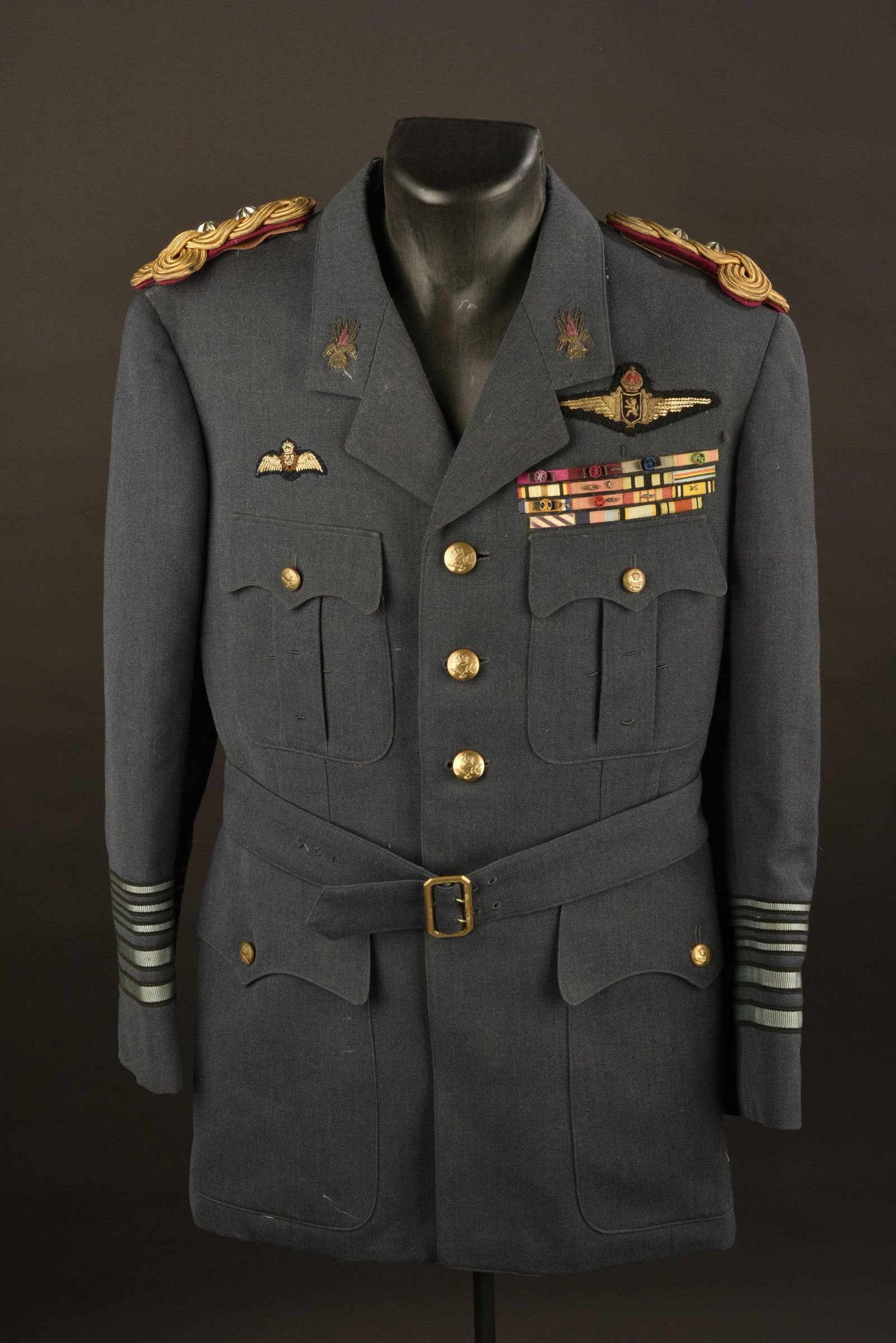 Vareuse de pilote belge. Belgian officer jacket: En tissu gris/bleu type RAF. Tous les boutons sont presents. Pattes d'epaules en fils or sur plateau rose, deux importantes etoiles en metal argente. Insignes de col et de poitrine en cannetille. Badg