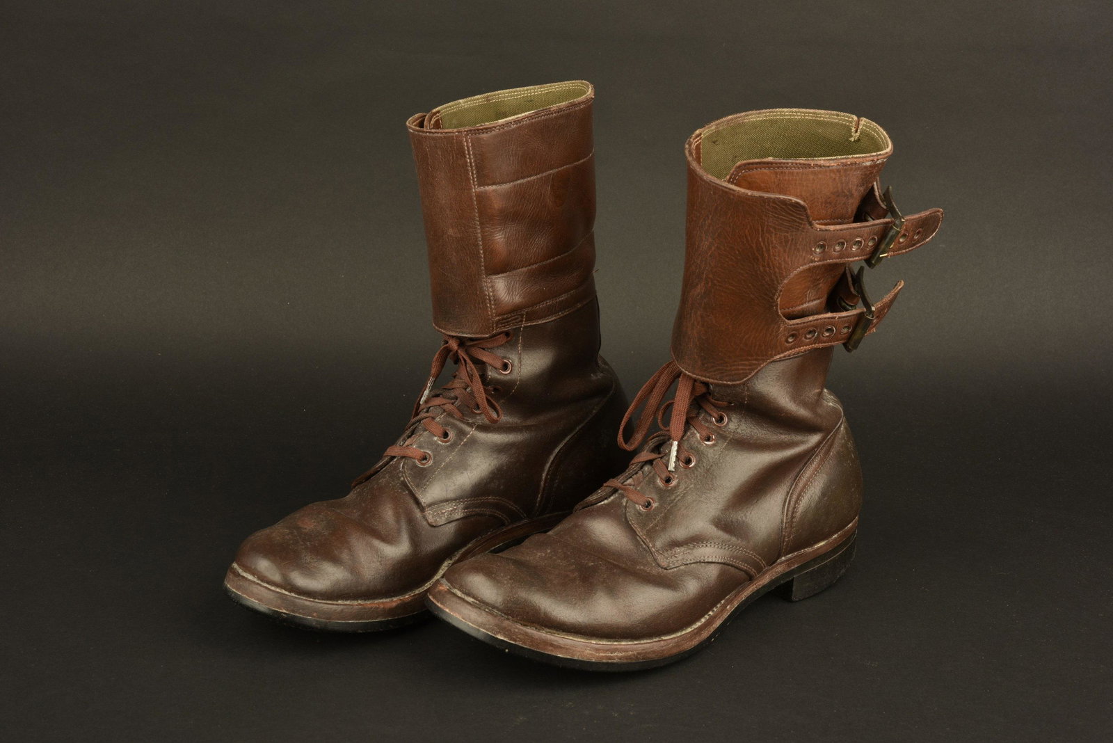 Buckle Boots: En cuir marron, sept Å“illets de laÃ§age, les lacets sont prÃ©sents. JambiÃ¨res attenantes disposant de leurs deux boucles de fermeture. Paire homogÃ¨ne. Semelles talons usÃ©s, reste de t