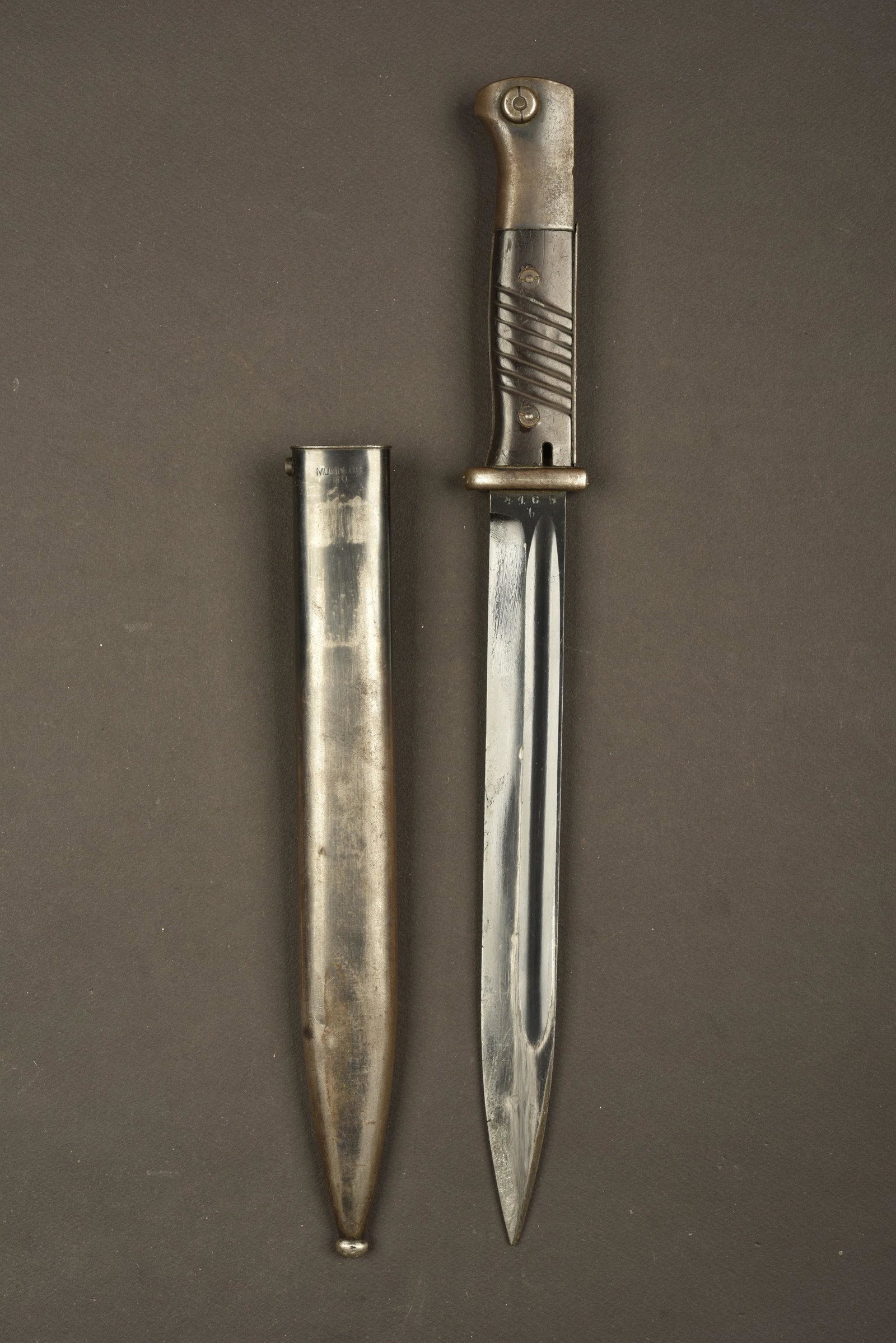Baionnette 98K. Bayonet 98K: Plaquettes en bakÃ©lite, maintenues par deux rivets. Lame dans sa couleur d'origine Ã 90%, fabrication Mundlos, numÃ©ro 4169b. Fourreau en mÃ©tal, couleur d'origine Ã 40%, numÃ©ro 4169b,