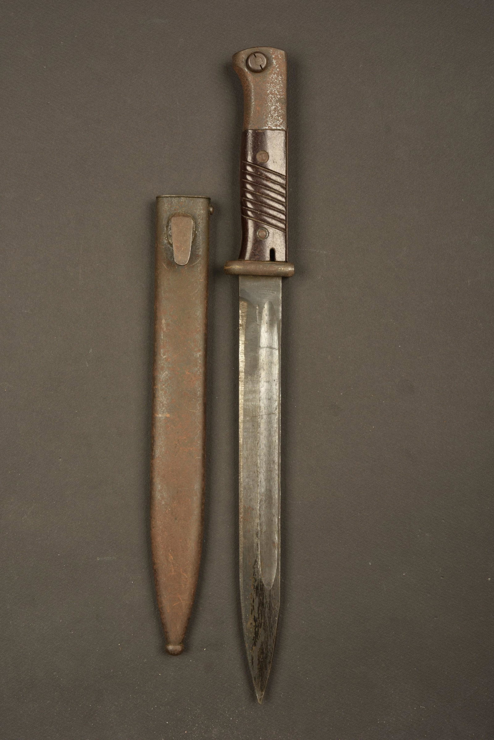 Baionnette 98K. Bayonet 98K: Plaquettes en bakÃ©lite, maintenues par deux rivets. Lame dans sa couleur d'origine Ã 95%, lÃ©gÃ¨rement affÃ»tÃ©e, fabrication WKC, numÃ©ro illisible. Fourreau en mÃ©tal, couleur d'or