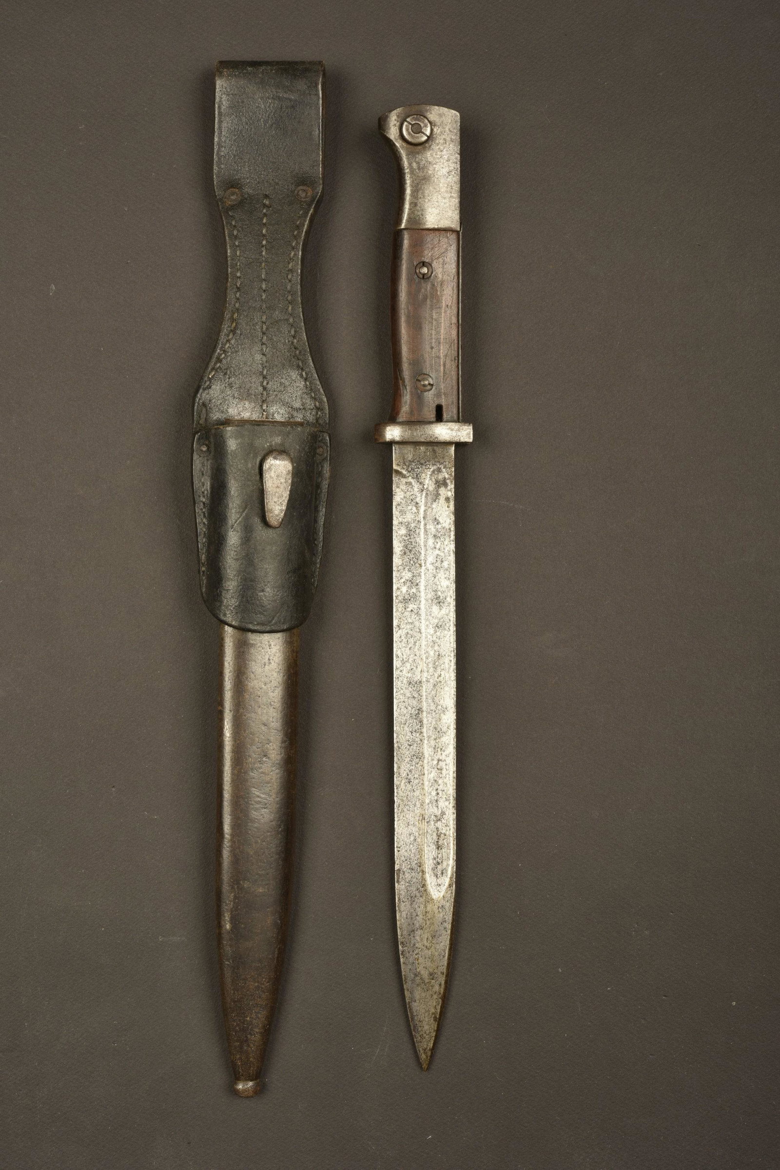 Baionnette 98K. 98K Bayonet: Plaquettes en bois, maintenues par deux rivets. Lame dans sa couleur d'origine Ã 5%, oxydÃ©e, fabrication 42 COF, numÃ©ro 1919aa. Fourreau en mÃ©tal, peinture Ã 10%, numÃ©ro 3190. Gousse