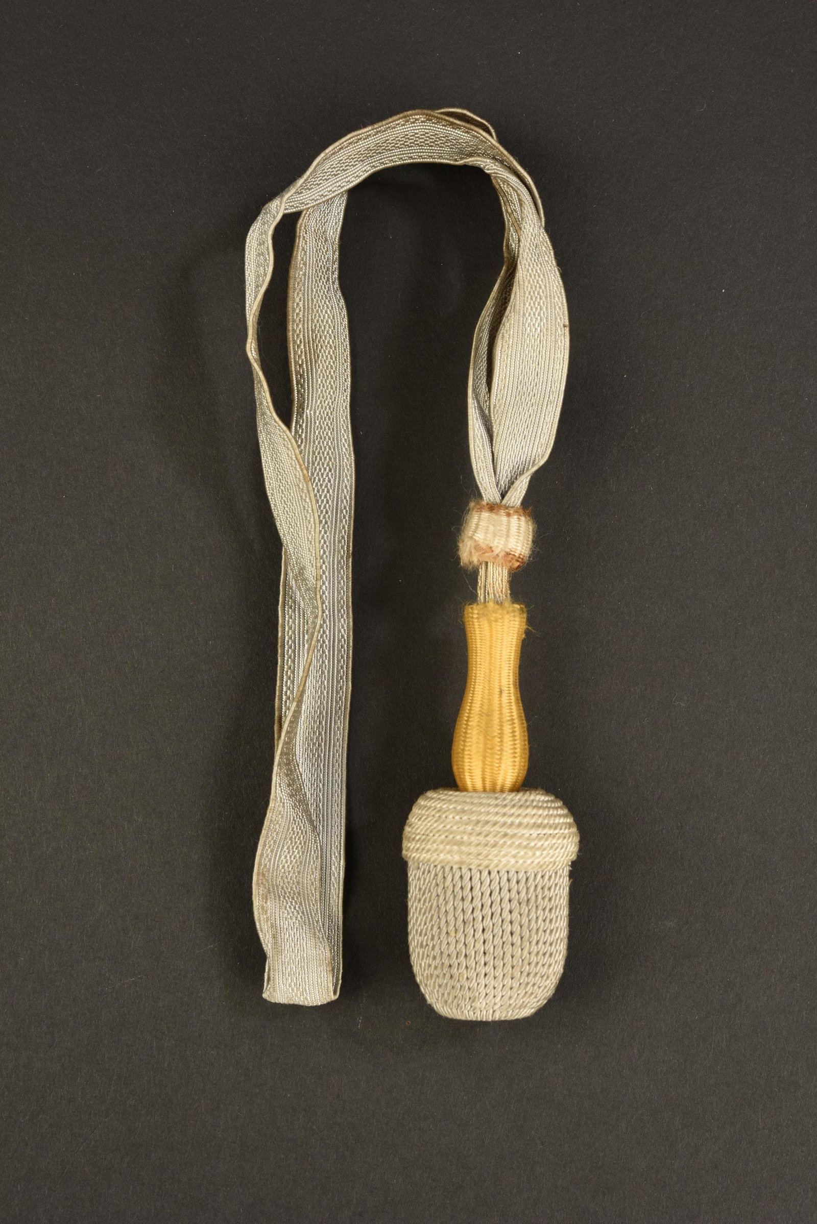 Dragonne de baionnette allemande. German bayonet strap: Galon d'argent, tige de couleur jaune, base du gland de couleur blanc, gland couleur argent, partie centrale du gland, couleur argent. A noter une certaine usure et patine de la piÃ¨ce. Silver braid