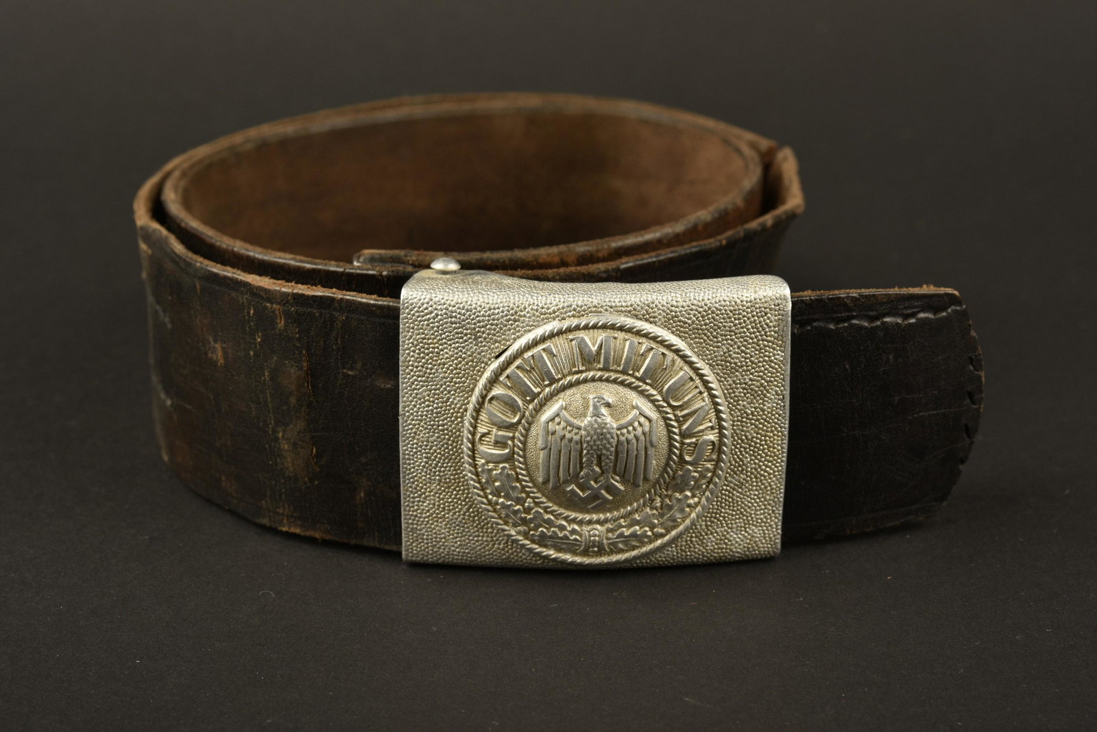 Ceinturon de la Heer. German belt: Ceinturon en cuir noir, prÃ©sentant une dÃ©chirure, sans marquages visibles. Boucle en mÃ©tal grenelÃ©, couleur argentÃ© Ã 70%. Fabrication en deux parties. Sans marquages visibles. A not