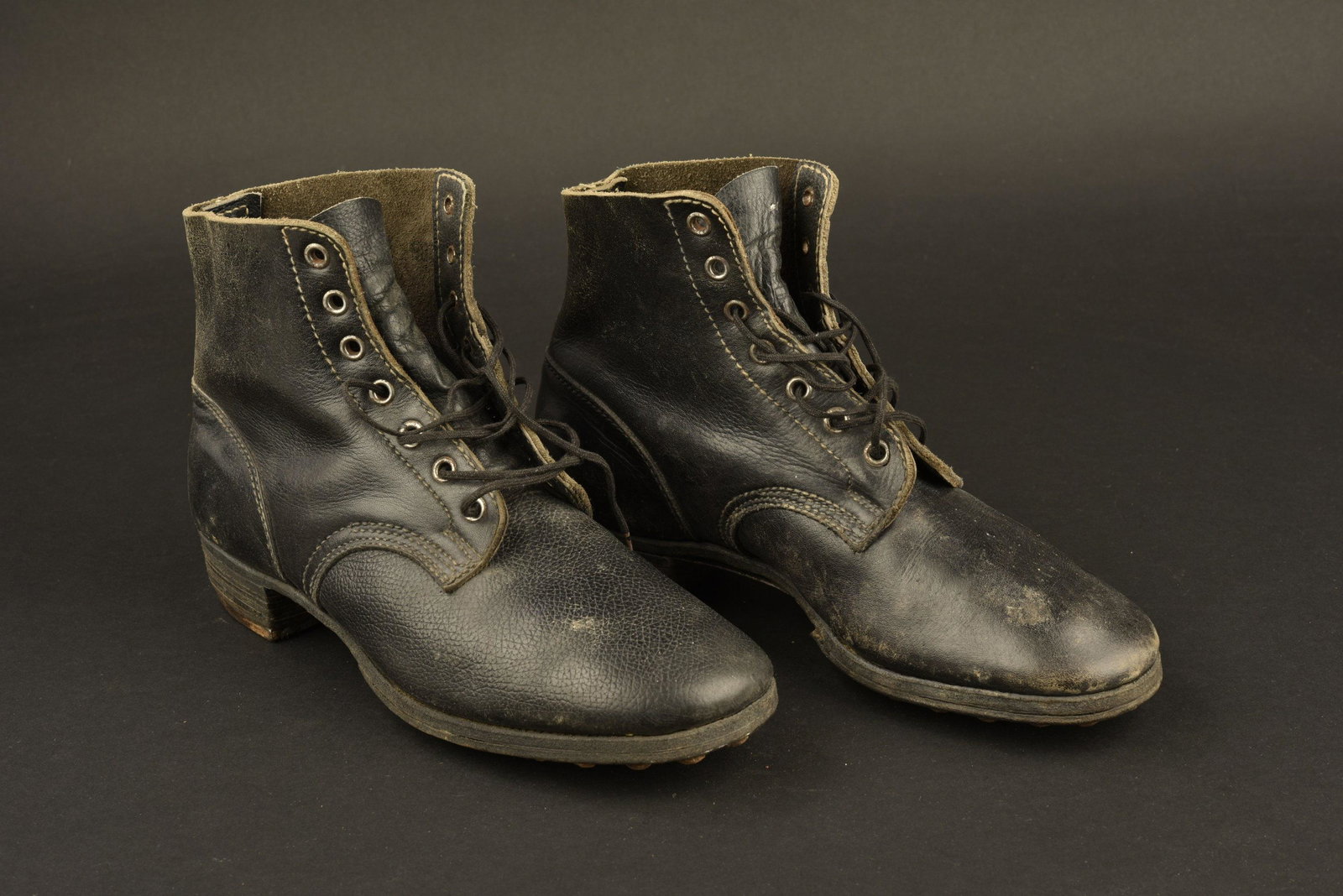 Brodequins allemand. German ankle boots: En cuir lisse noir, huit oeillets de lacage. Les lacets sont posterieurs. Paire non homogene. Semelles cloutees et ferrees. Marquages sous la semelle 7. Approximativement une pointure 41/42 francaise.