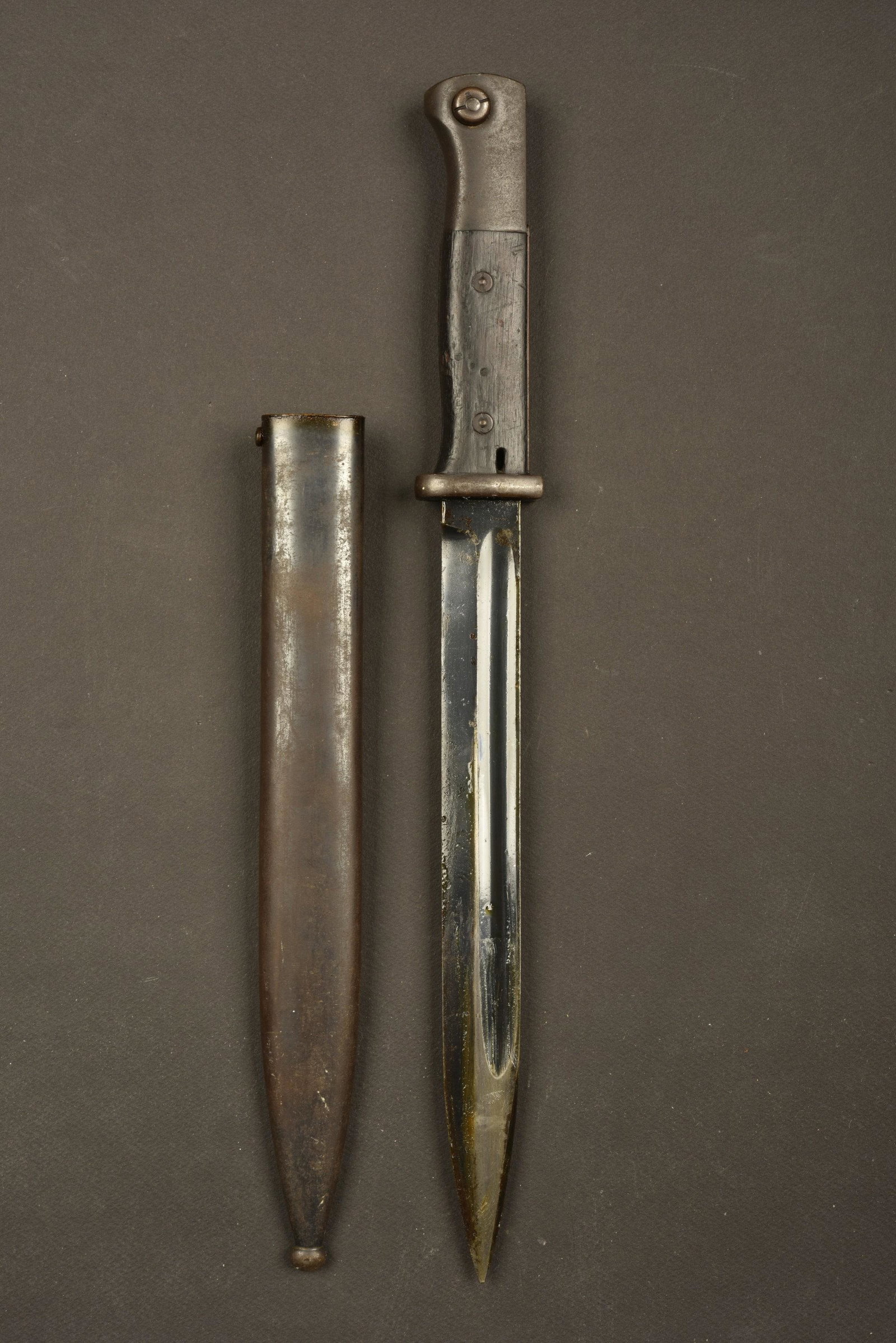 Baionnette 98K. 98K Bayonet: Plaquettes en bois, maintenues par deux rivets. Lame dans sa couleur d'origine a 90%, fortement huilée. Garde marquee 9167 i. Fourreau en metal, couleur d'origine Ã 40%, sans marquages visibles. A
