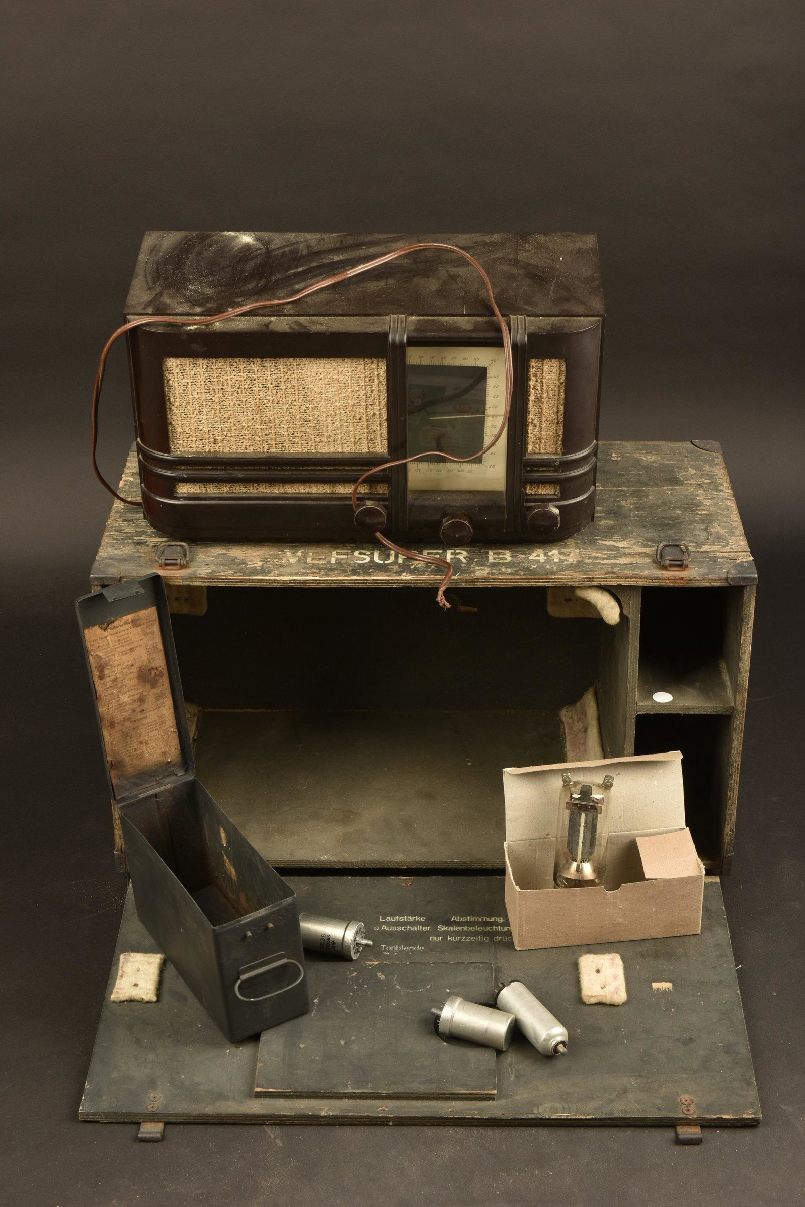 Radio Vefsuper B 417 dans sa caisse: Caisse en bois, peinture Ã 60%, poignee en metal, les crochets de fermeture sont complets. Marquages sur le haut de la caisse Vefsuper B 417. La notice est absente. Radio en bakelite, toutes les to