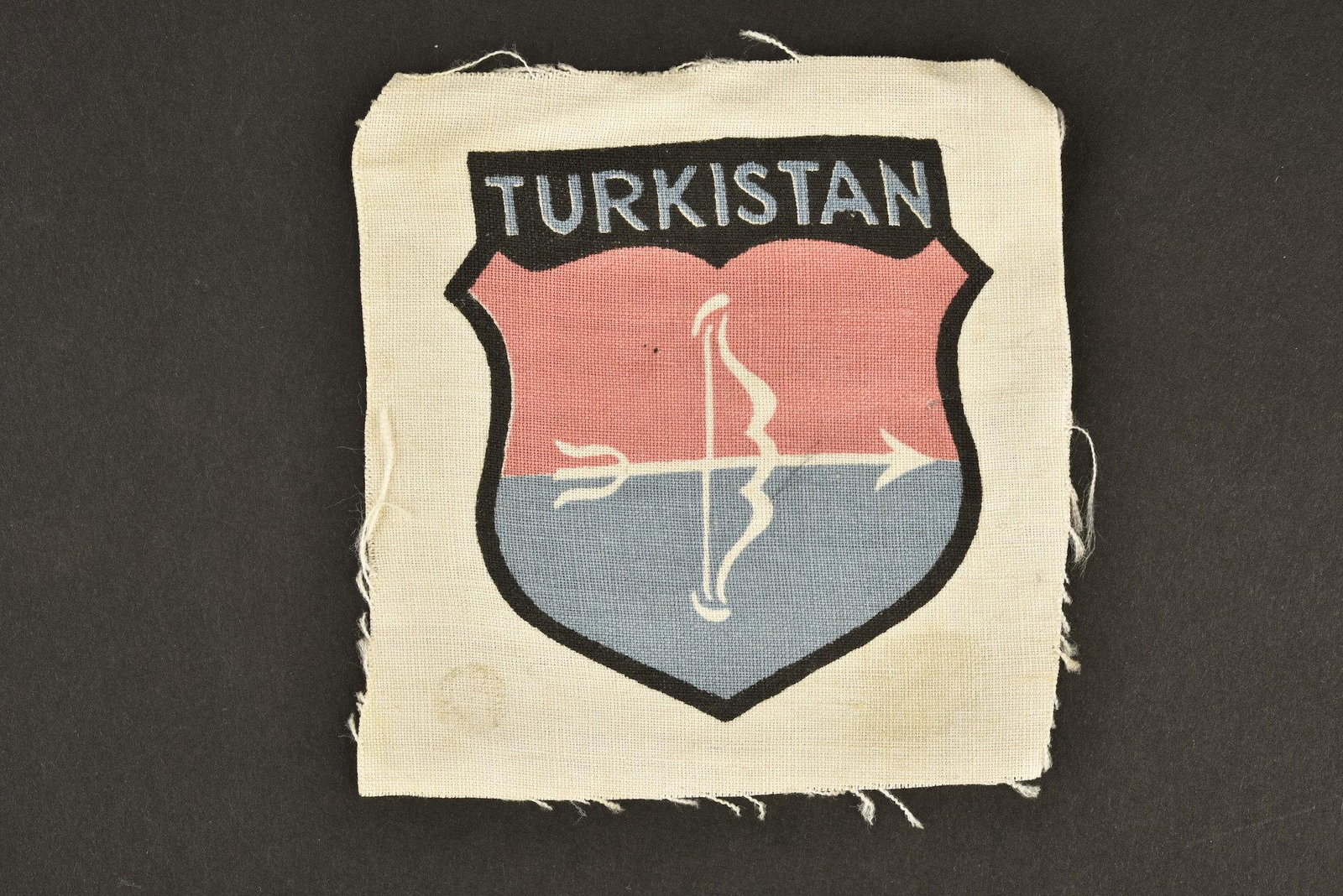 Insigne des volontaires du Turkistan. Turkistan: Insigne tisse jamais monte, bien marque Turkistan. A noter une certaine patine de la piece, ainsi que quelques tÃ¢ches. Woven badge never mounted, well marked Turkistan. Note a certain patina of the
