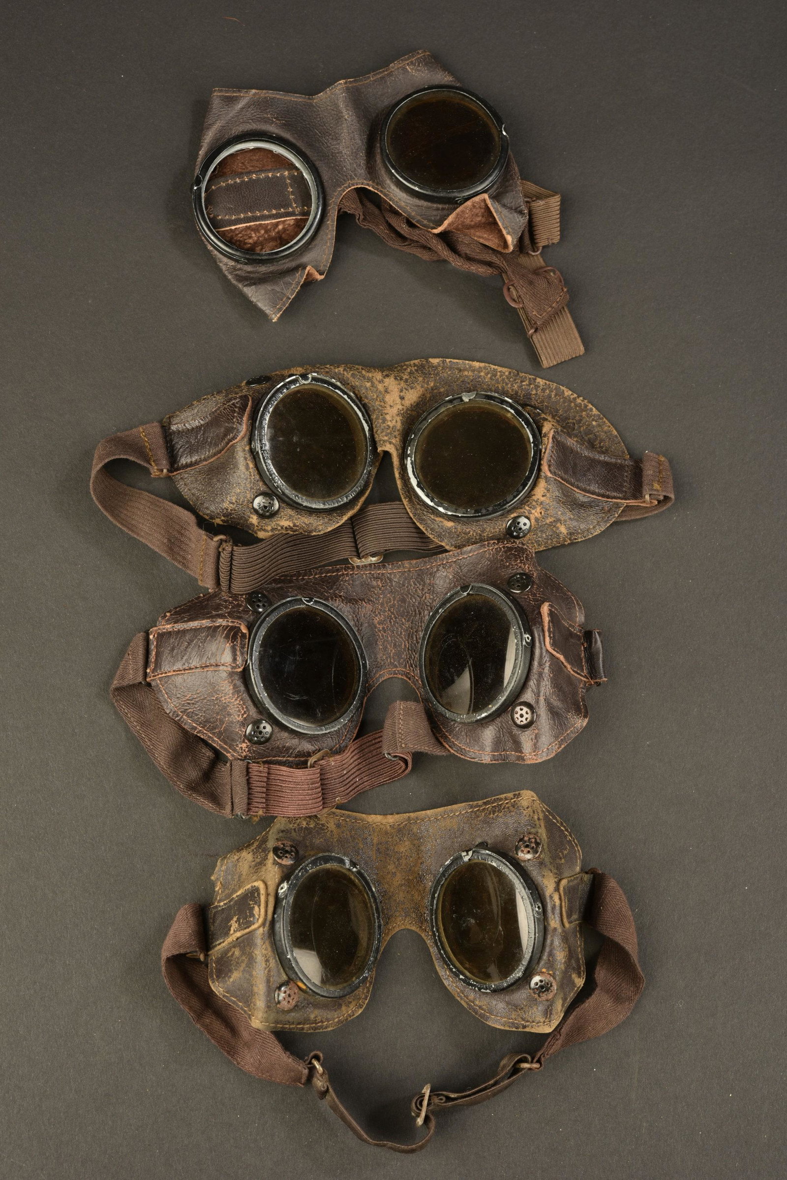 Lunettes anti-poussiere allemande. German dust glasses: Quatre paire en cuir marron, et armatures mÃ©talliques. Les elastiques sont presents et majoritairement souples. Verres fumes. Un verre manquant. A noter une certaine usure et patine des pieces. Fou