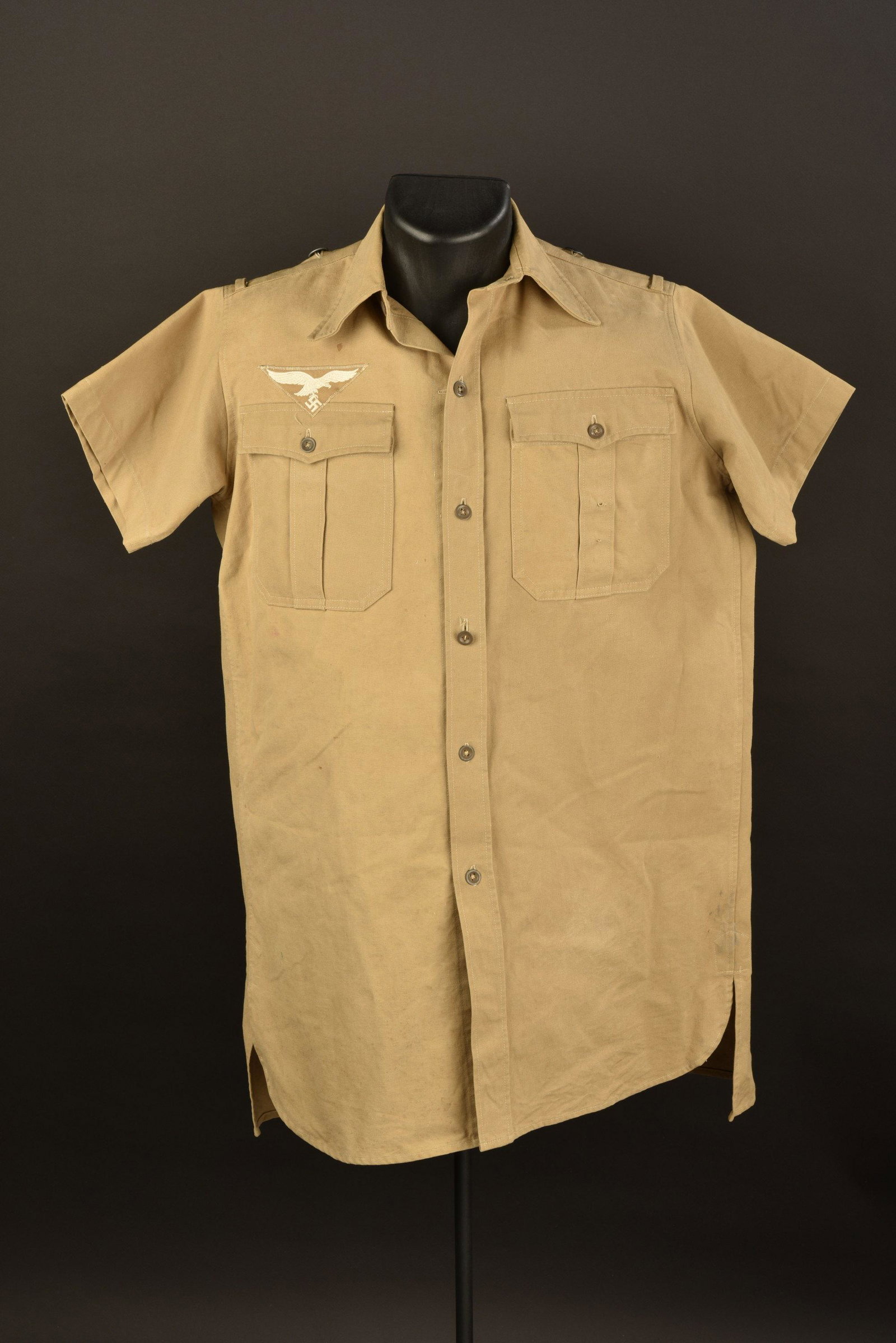 Chemisette tropicale LW. Luftwaffe tropical shirt: En tissu coton beige. Tous les boutons sont presents. Aigle de poitrine brode sur fond sable, monte machine. Manches courtes. Taille 40 tamponnee dans le col. A noter une legere usure de la piece, ain