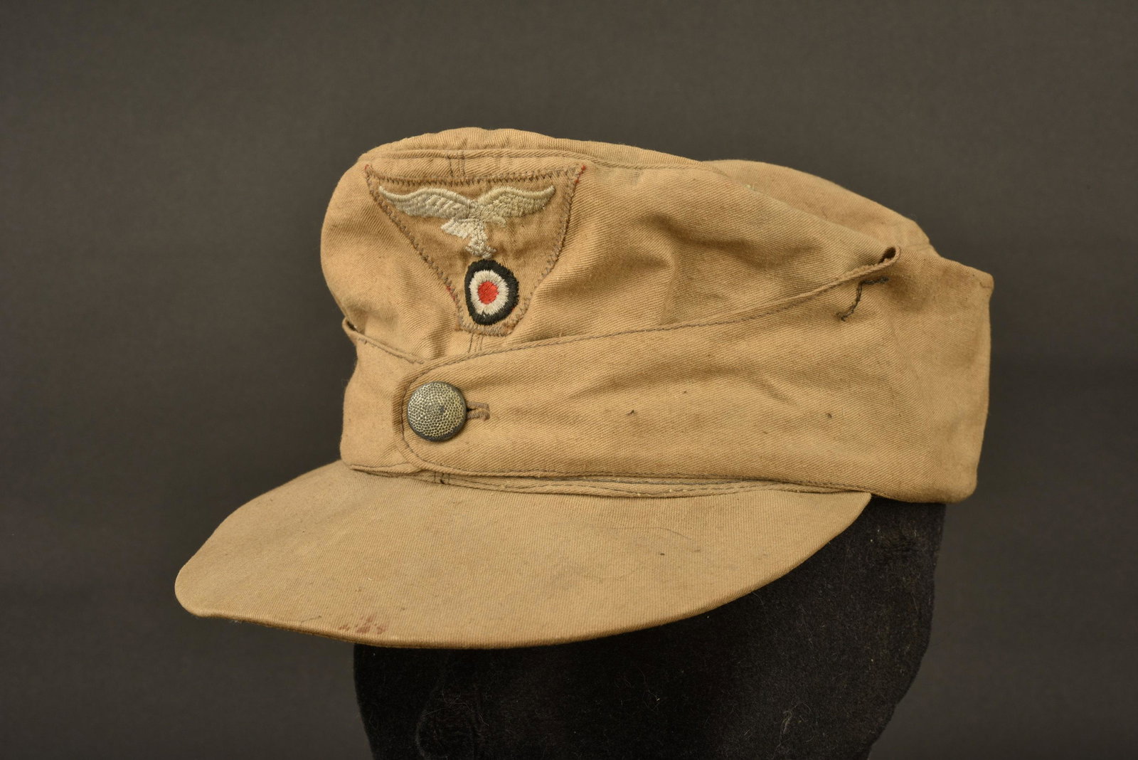 Casquette tropical Luftwaffe. Luftwaffe tropical cap: En tissu coton couleur sable. Rabat fermant par un bouton. Insigne brode et monte machine. Interieur double en tissu coton rouge. Sans marquages visibles. A noter une certaine usure et patine de la pi