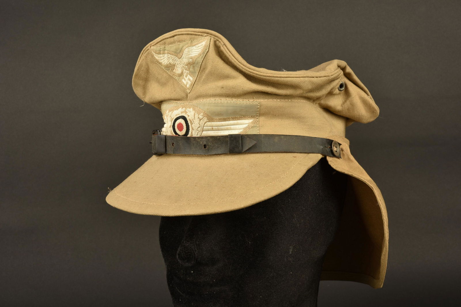 Casquette tropical Maier. H Maier tropical cap.: En tissu couleur sable. Visiere en parfait etat. Fausse jugulaire en cuir, maintenue par deux boutons. Insignes Bevo montes machine. Protege nuque en toile sable, fixe par trois boutons. Demi bandeau