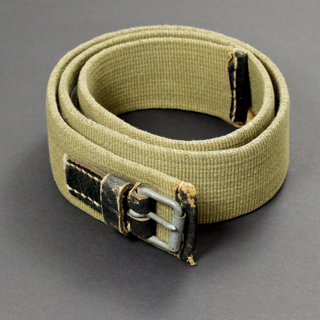 Ceinture tropical. Tropical belt.: En toile sable et cuir noir. Boucle a un ardillon present. Sans marquages visibles. A noter une certaine usure et patine de la piece. In sand canvas and black leather. Buckle with a tang present. Wi