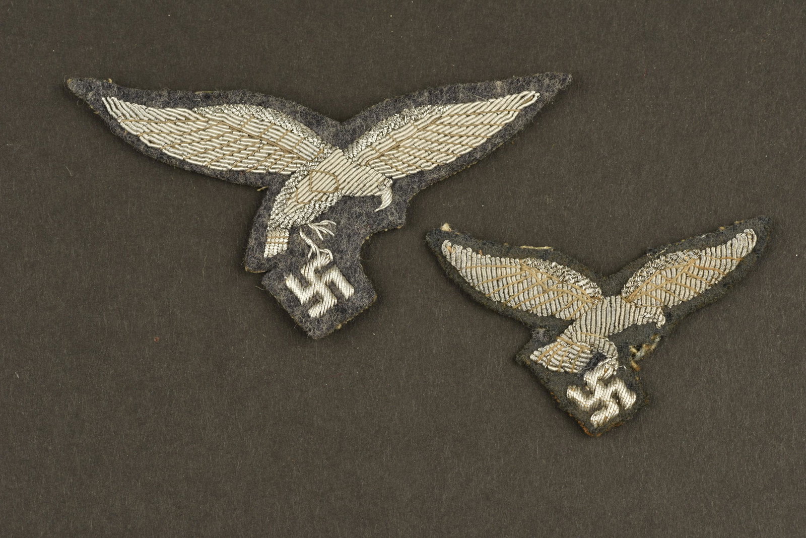 Insigne officier LW. LW officer insignia: Comprenant un aigle de coiffure du premier type en cannetille argent sur fond en gabardine gris/bleu, démonté d'une coiffure. Un aigle de poitrine du premier type en cannetille argent, monte sur fon