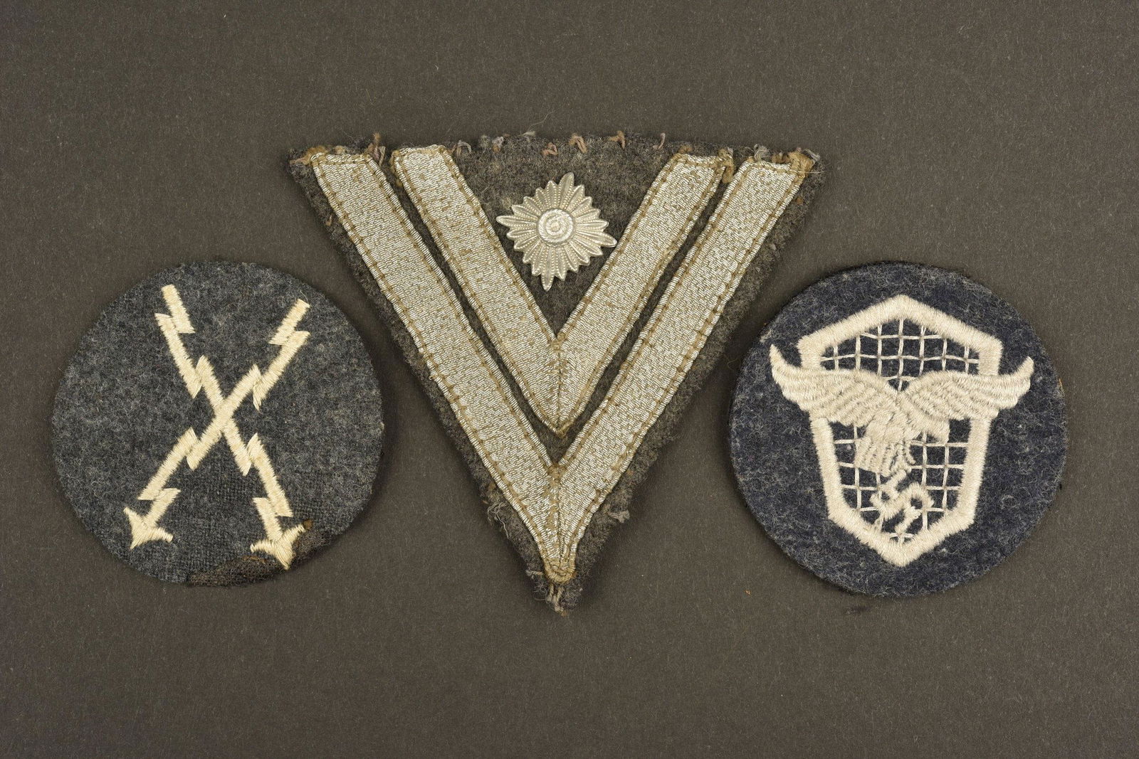 Insignes tissu de la Luftwaffe. LW insignia set: Comprenant un grade de manche de Stabsgefreiter sur fond en drap gris/bleu. Deux insignes de specialite, en drap gris/bleu, quelques manques. A noter une certaine usure et patine des piÃ¨ces. Includ