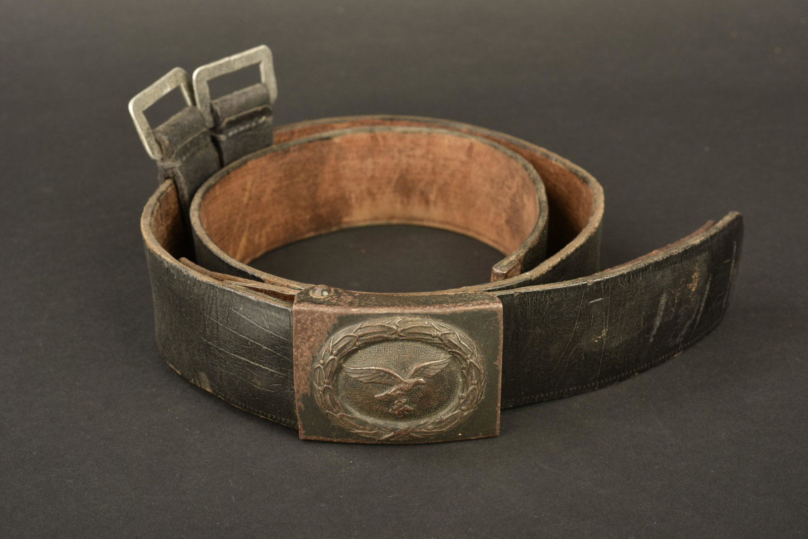 Ceinturon de la Luftwaffe. Luftwaffe belt.: Ceinturon en cuir noir. Bouclerie en metal, fortement oxydee. Taille 100. La patte de reglage est presente, mais craquelee. Deux passant de fixation du brelage complets, dates 1936. Boucle de ceinturo