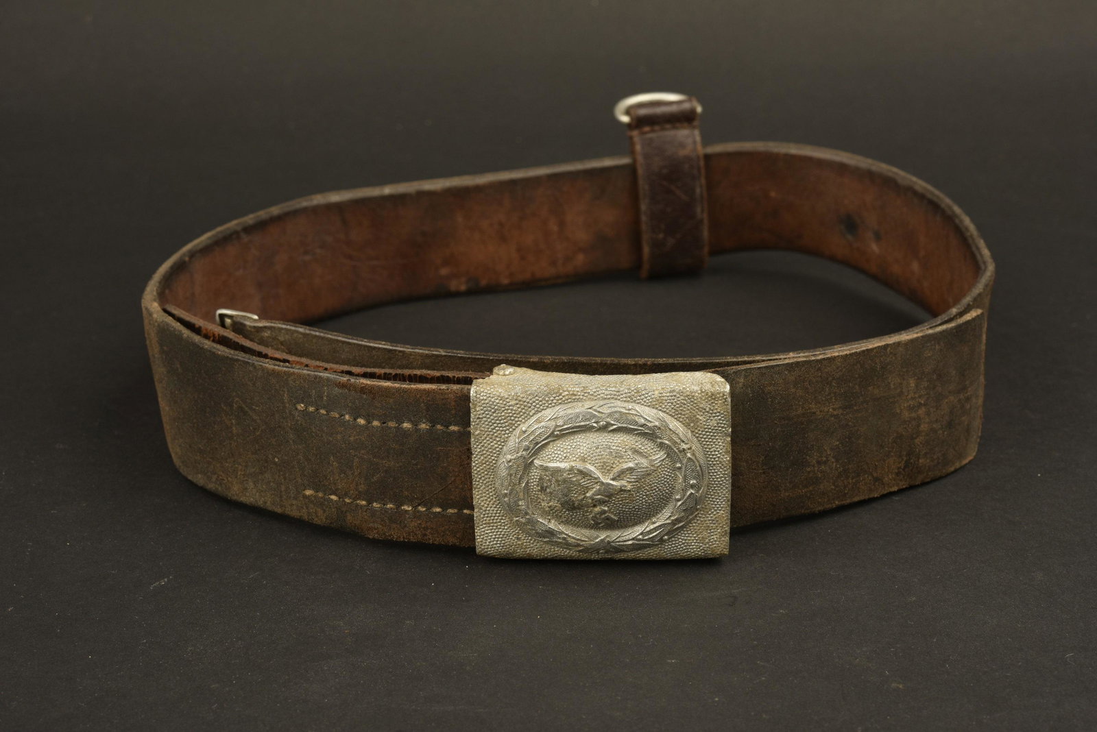 Ceinturon de la Luftwaffe. Luftwaffe belt.: Ceinturon en cuir noir, retaille Ã un bout, bouclerie en metal, peinture absente. Marquages illisibles. Patte de reglage presente. Taille 100. Boucle en aluminium de fouille, fabrication A & V. Un 