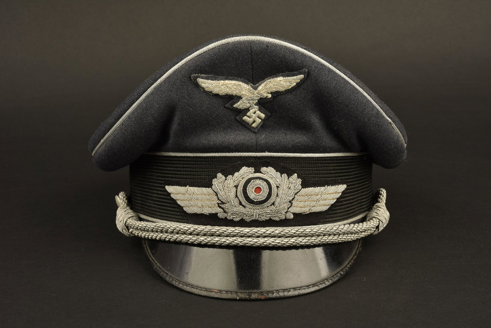 Casquette officier LW. LW Officer visor cap: En gabardine gris/bleu, triple lisere argent. Cocarde et feuilles de chene en cannetille argent. Fausse jugulaire presente. Aigle en cannetille, oxyde, monte d'origine. IntÃ©rieur double en satinett