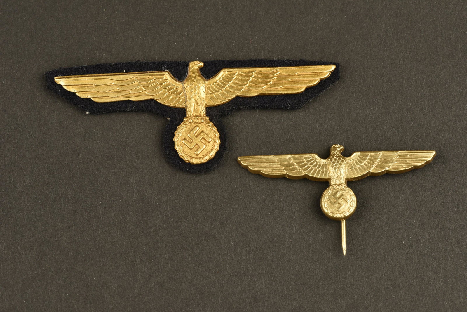 Insignes de la Kriegsmarine. Badges Kriegsmarine: Comprenant un aigle de coiffure en metal dore, attache complete, marquages JFS 40. Un aigle de poitrine en metal dore, monte sur un fond en drap noir. A noter une legere usure et patine des pieces. In
