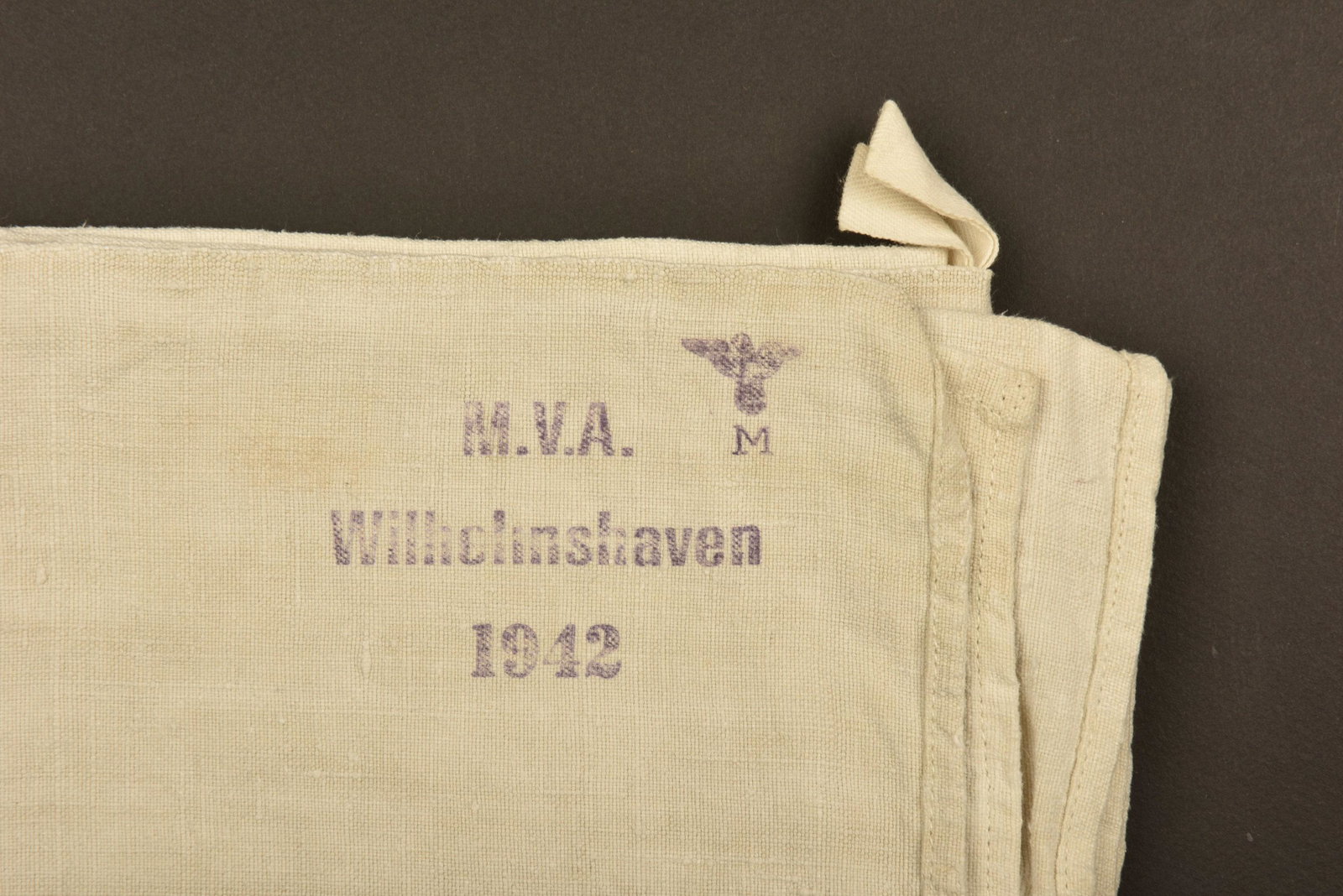 Serviette de la Kriegsmarine Wilhelnshaven. Towel KM: En tissu coton gris. Tampon de la Kriegsmarine present. Marquages MVA Wilhelmshaven 1942. A noter une certaine usure et patine de la piece, ainsi que quelques tÃ¢ches. In gray cotton fabric. Kriegsm