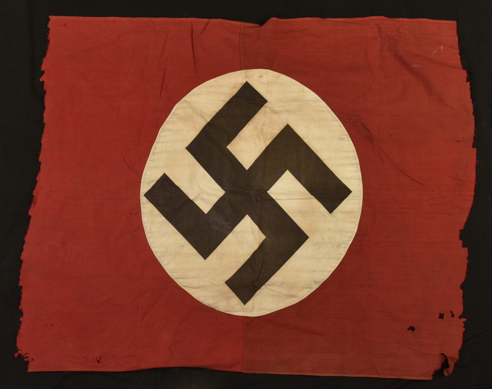German Flag La Palice. Drapeau allemand la Pallice: En tissu coton rouge, insigne national imprime et rapporte. Biface. Dimensions 120 x 110 cm. Sans marquages visibles. Drapeau incomplet, decouple d'un cote. Nombreuses marques d'usures, insigne décol