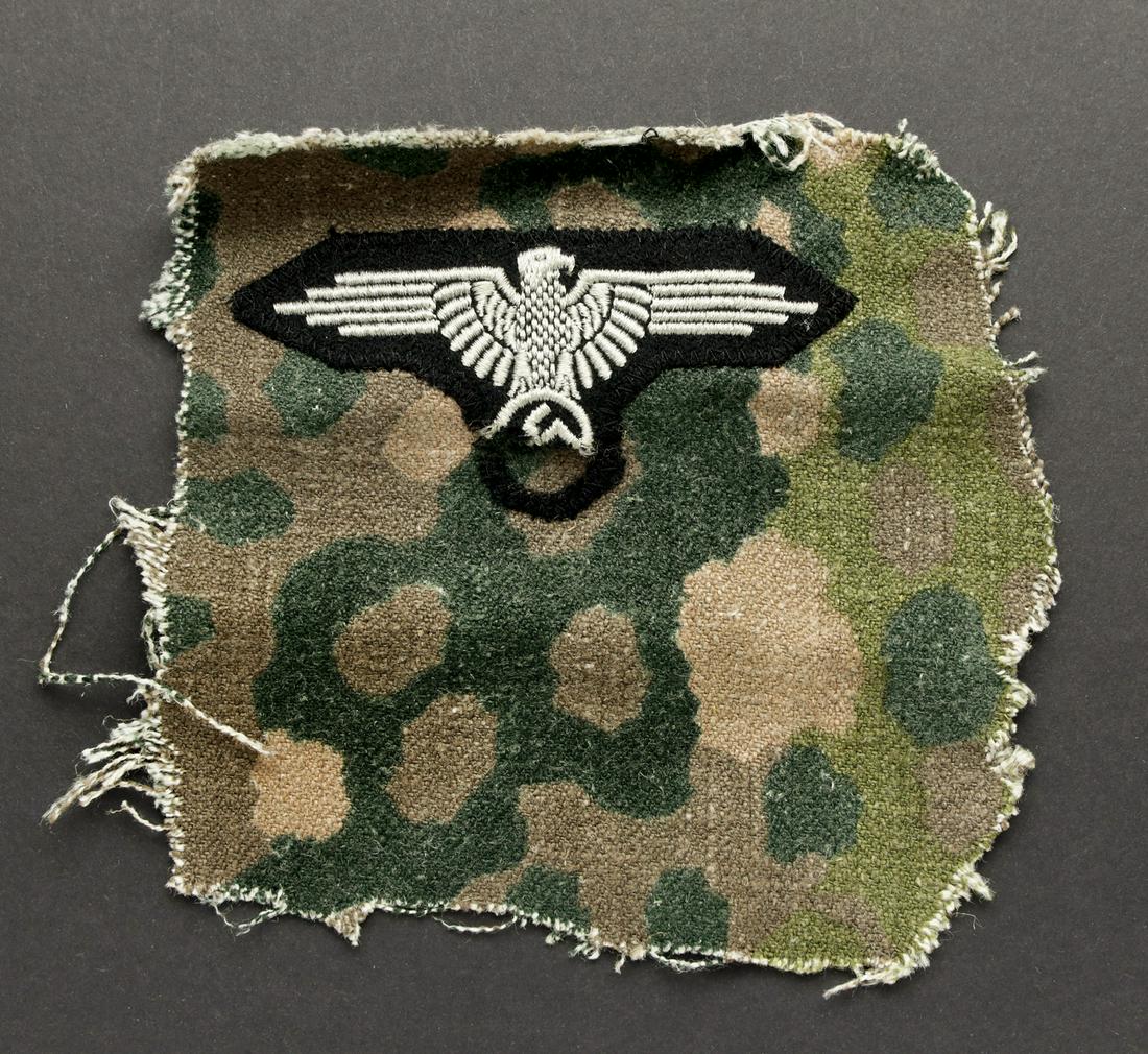SS eagle. Aigle de bras de la waffen ss: Aigle brode monte d'origine, sur fond de veste petit pois. L'insigne national est en parti manquant. Type de piÃece souvent decoupees par les GI US en guise de souvenir. Belle prise de guerre. A note