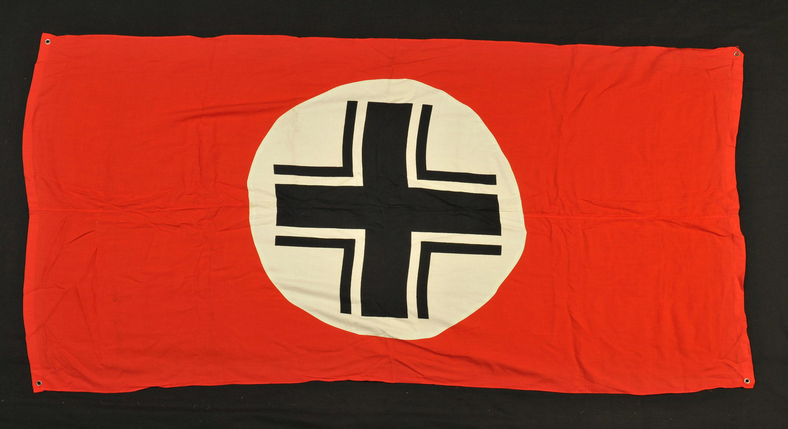 Drapeau de signalisation de vehicule allemand.: En tissu coton rouge, fabrication en deux parties, mono face, croix baltique imprimee et rapportee. Quatre oeillets en metal pesentant des marques d'oxydation. Sans marquages visibles. Dimensions 97 x