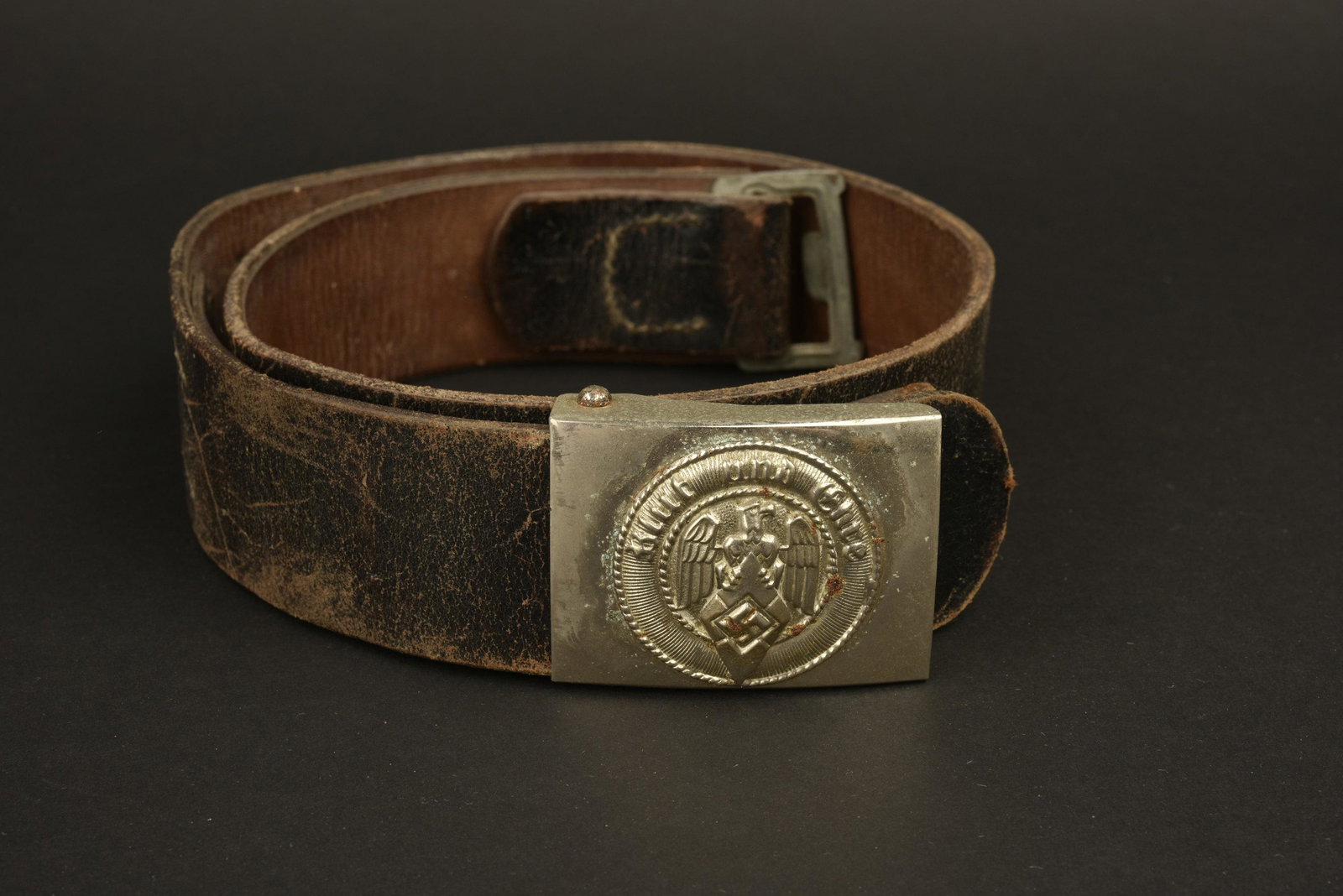Ceinturon HJ. HJ Belt.: Ceinturon en cuir noir, bouclerie en mÃ©tal partiellement dÃ©formÃ©. Taille 85, fabrication illisible, datÃ© 1944. Boucle en mÃ©tal nickelÃ©, sans marquage et sans garantie d'authenticitÃ