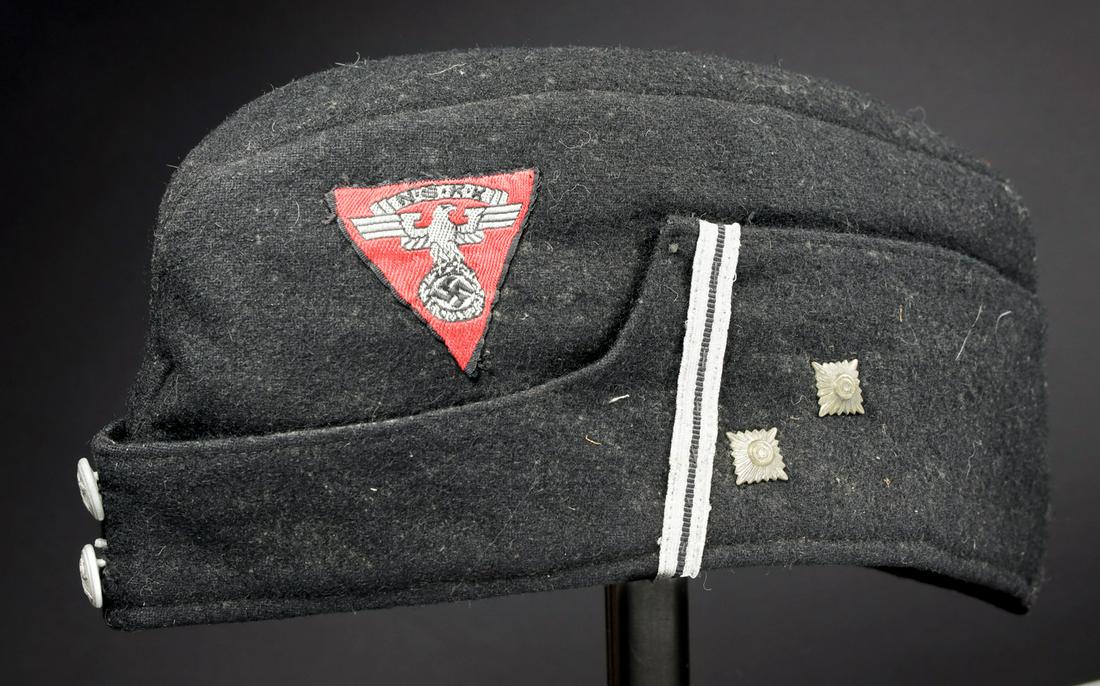 Calot officer NSKK. NSKK officer cap: En drap noir, deux boutons portant l'insigne du NSKK. Galon argent sur le rabat et deux clous mÃ©talliques, indiquant le grade d'ObertruppenfÃ¼hrer. Insigne NSKK tissÃ© sur fond rouge, correspon