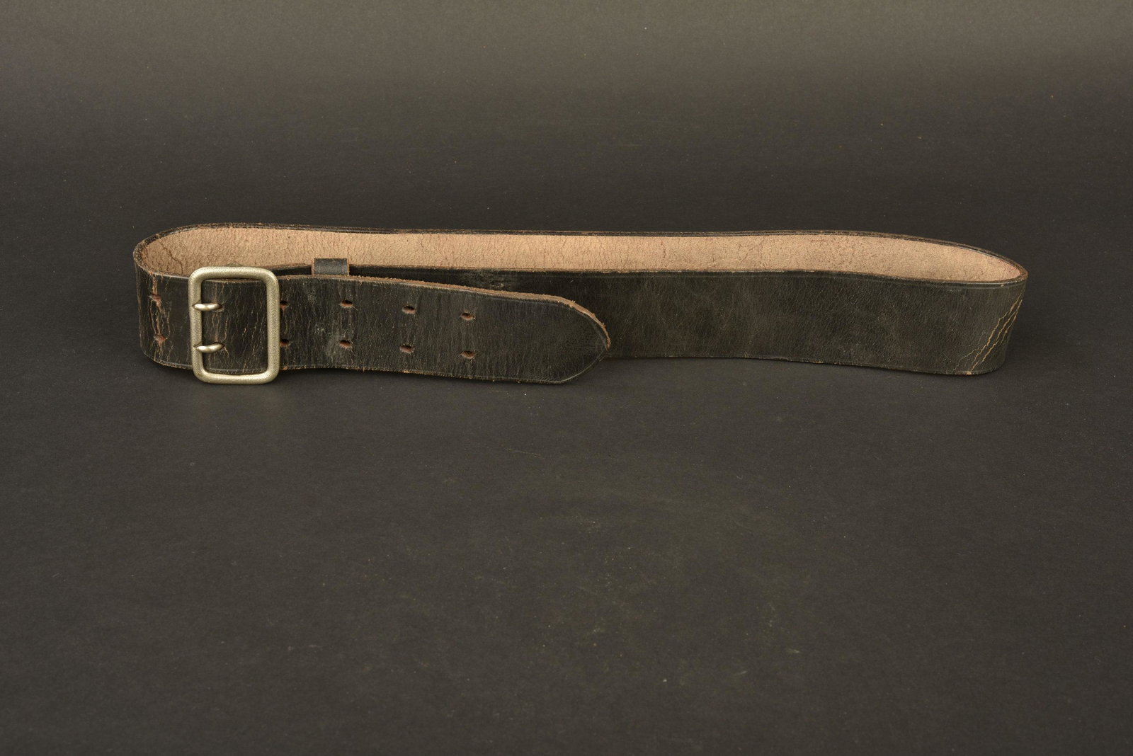 Ceinturon RZM. RZM Belt.: En cuir noir, marquages Deutsches Leder KernstÃ¼ck 472. Passant en cuir complet. Boucle en mÃ©tal grenelÃ© Ã deux ardillons, fabrication RZM 17. A noter une certaine usure et patine de la pi�