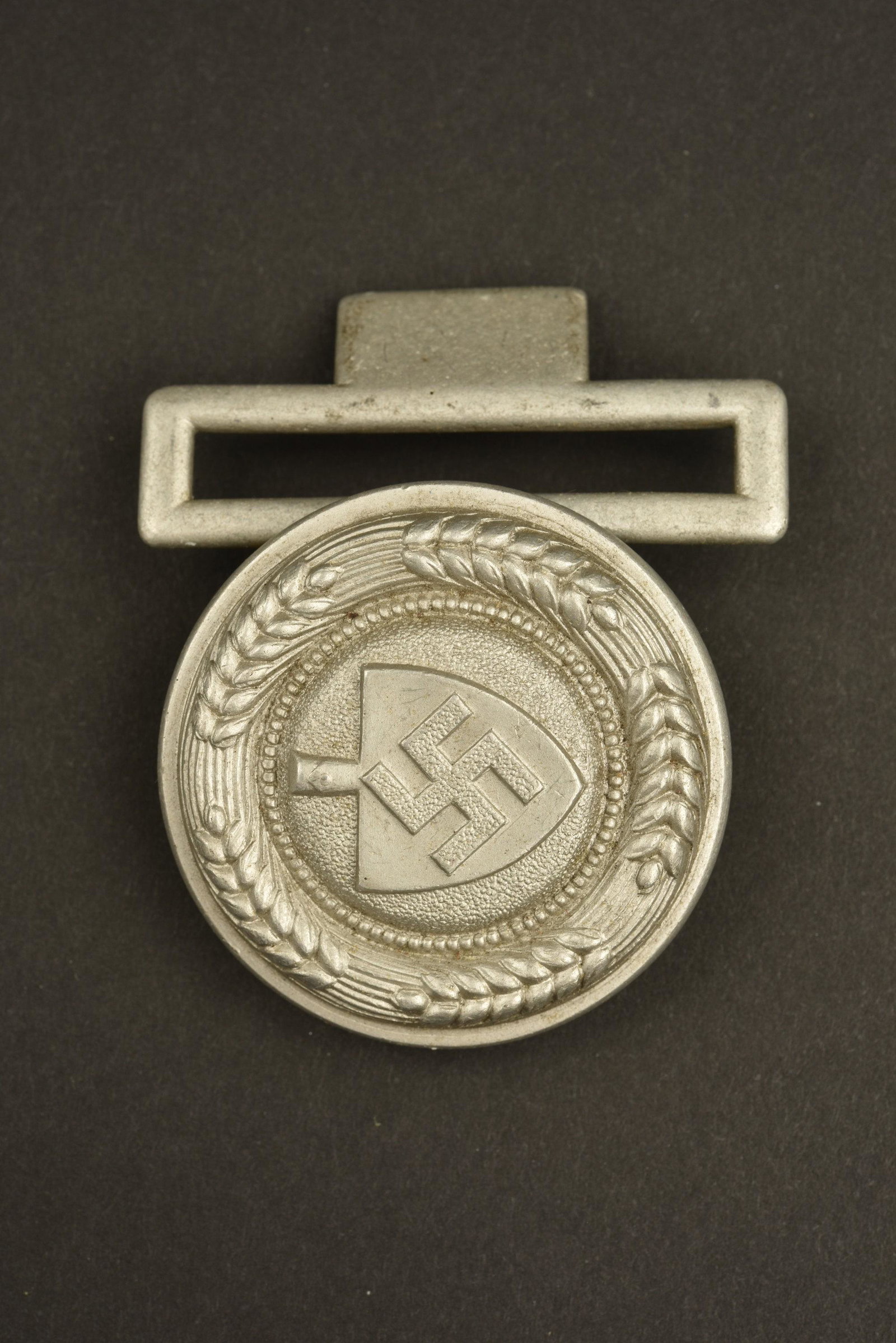 Boucle officier RAD. RAD officer belt buckle: En aluminium, crochet de fermeture absent. Fabrication CLC. A noter une lÃ©gÃ¨re usure et patine de la piÃ¨ce. Aluminum, missing closing hook. CLC manufacturing. Note a slight wear and patina of